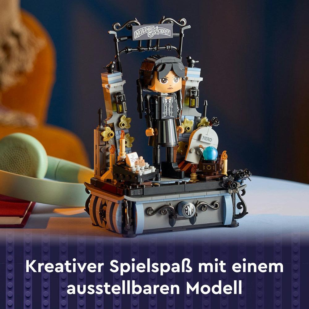 Lego-Set von Wednesday Addams mit einem Modell der Nevermore Academy, auf einem Tisch mit blauem Tuch.