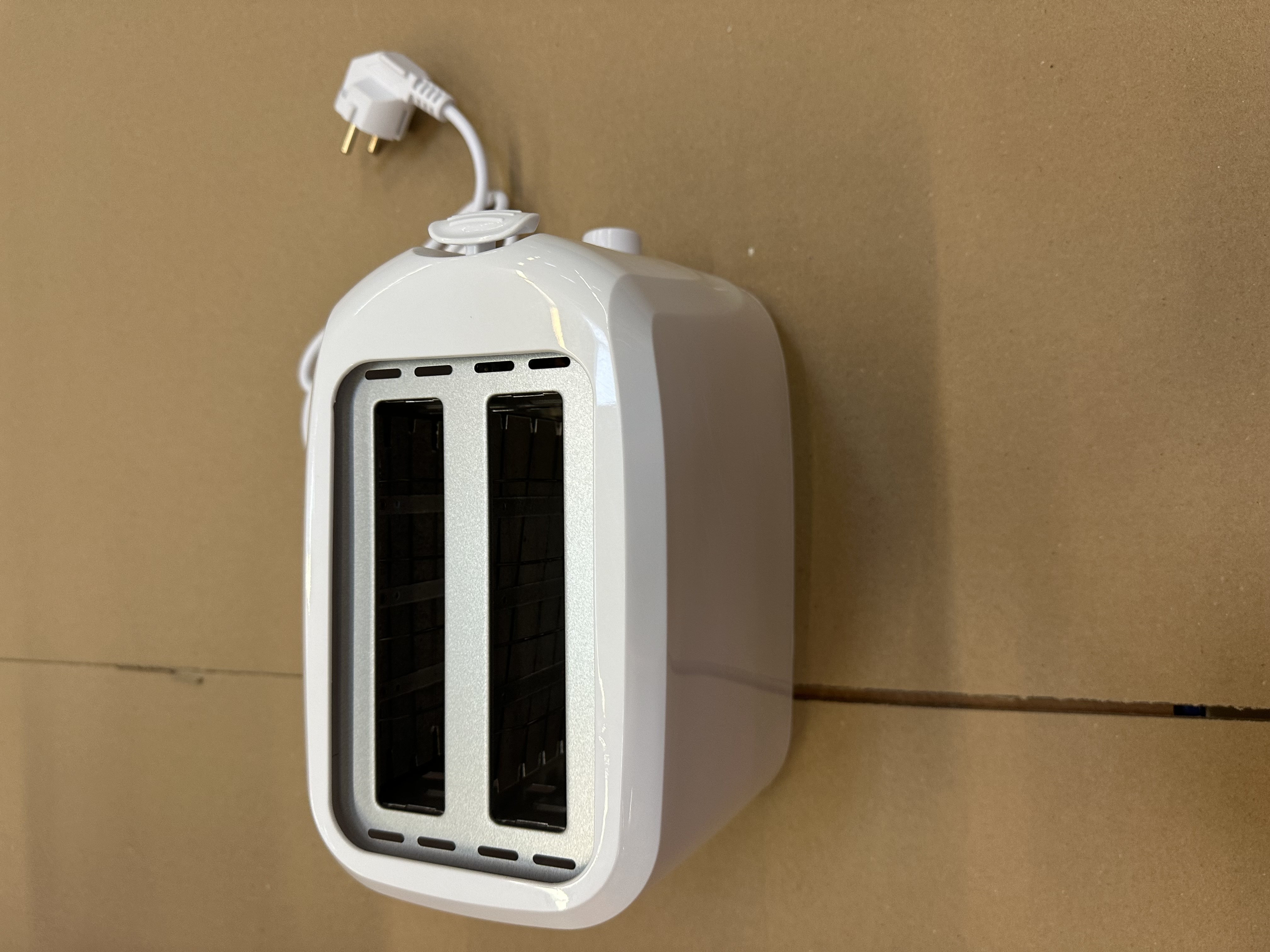 Biały toster z dwoma otworami. Widoczny przewód zasilający i wtyczka.