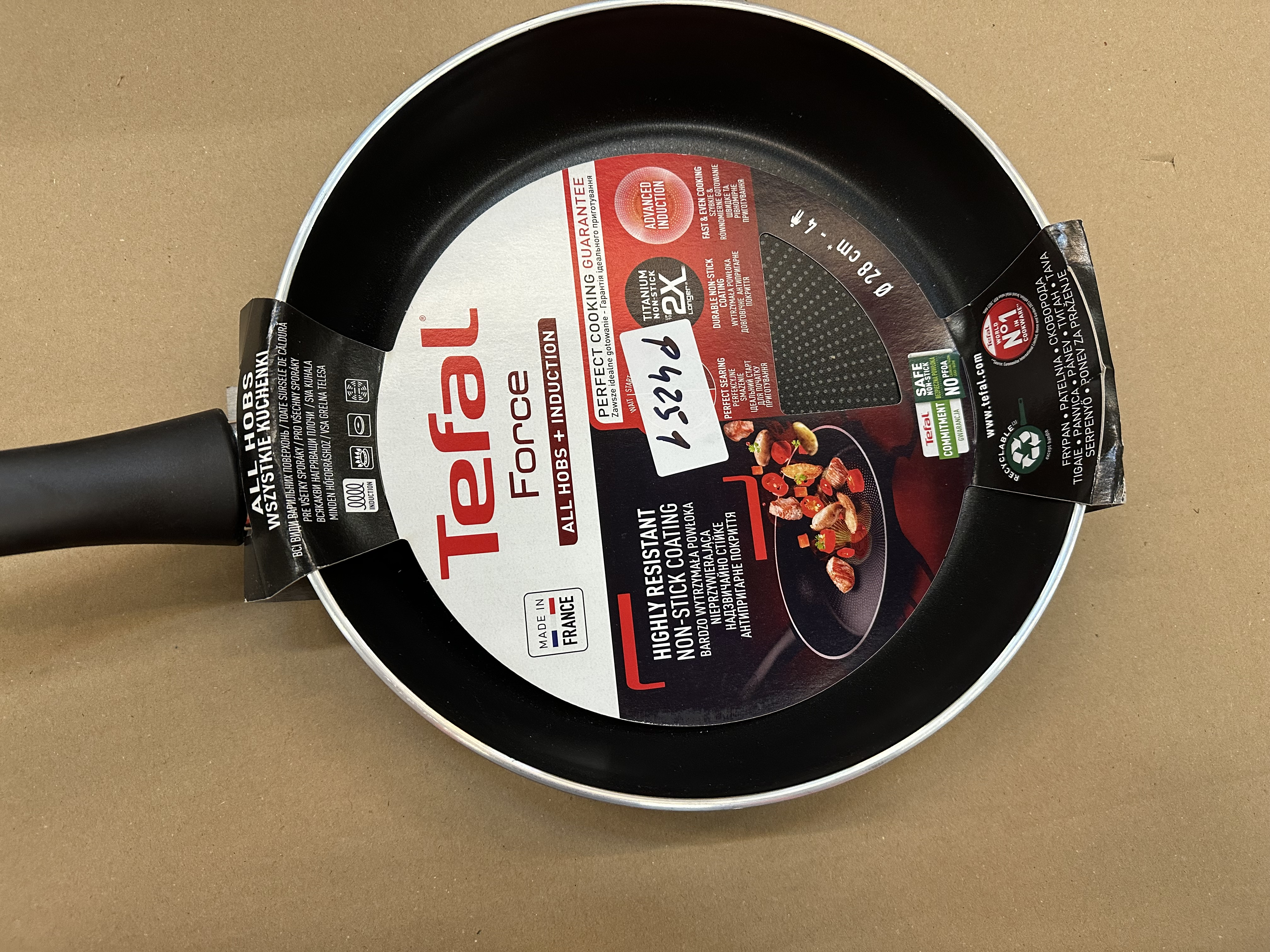 Patelnia Tefal Force, czarne wnętrze, opakowanie z tekstem i obrazami, metalowy uchwyt.
