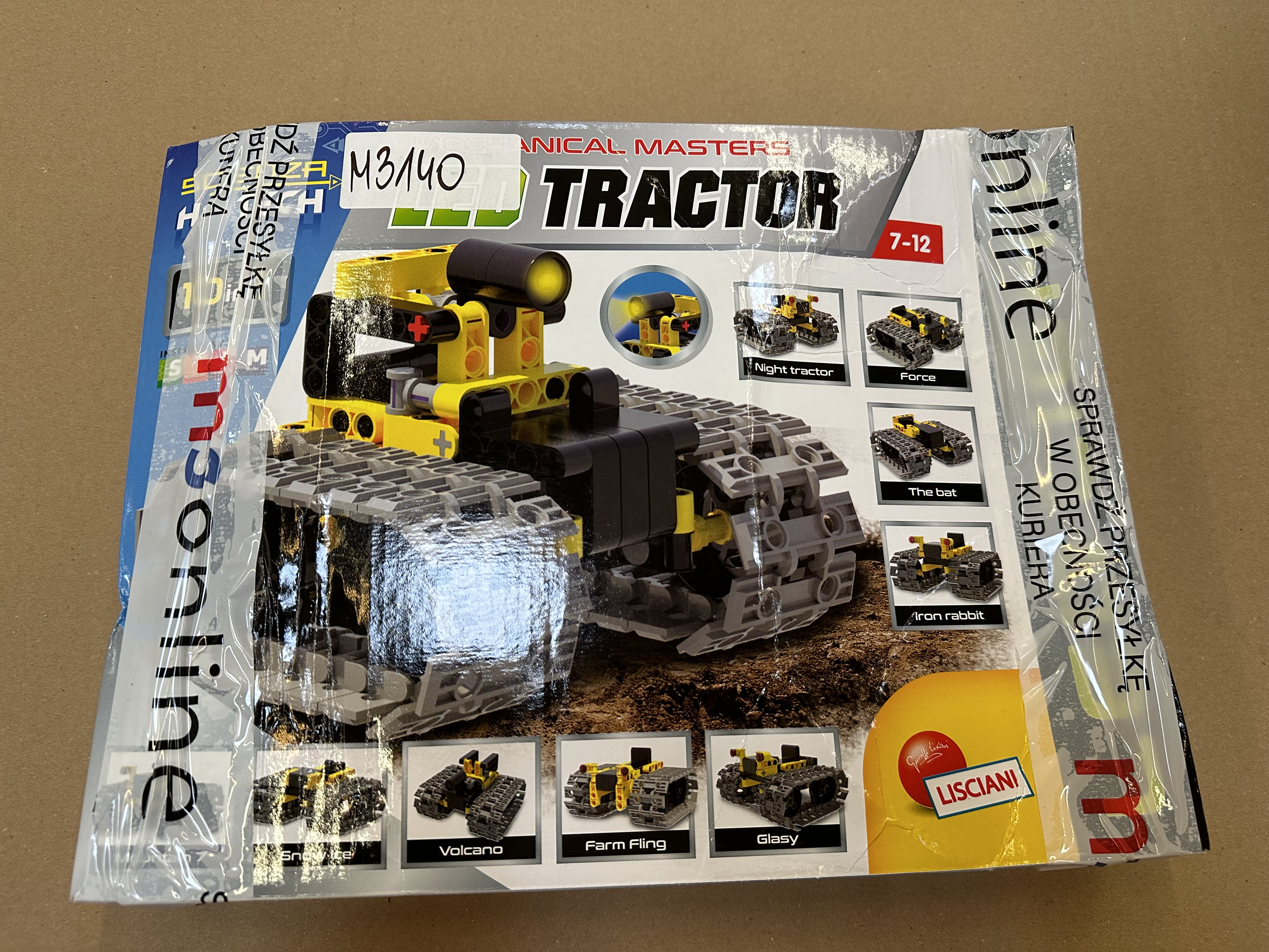 Zabawkowy traktor w pudełku. Pudełko jest niebieskie i pokazuje zdjęcia.