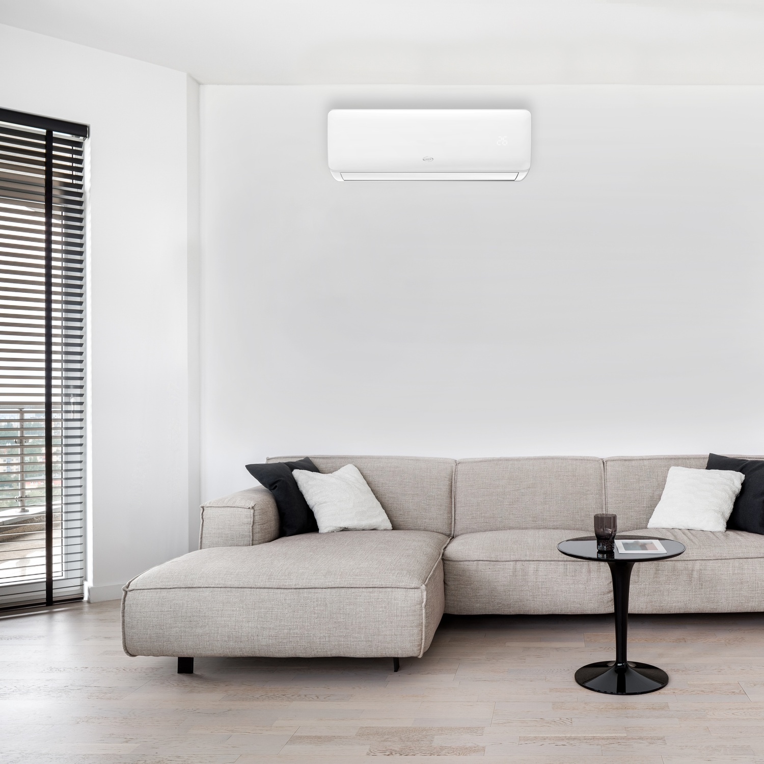 Un soggiorno con condizionatore a parete, divano, tavolo e finestra.