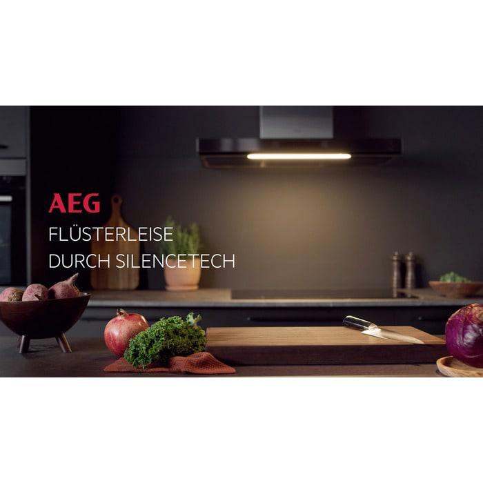 Küchenszene mit Früchten und einem Holzbrett. Über dem Kochfeld befindet sich eine schwarze Dunstabzugshaube.