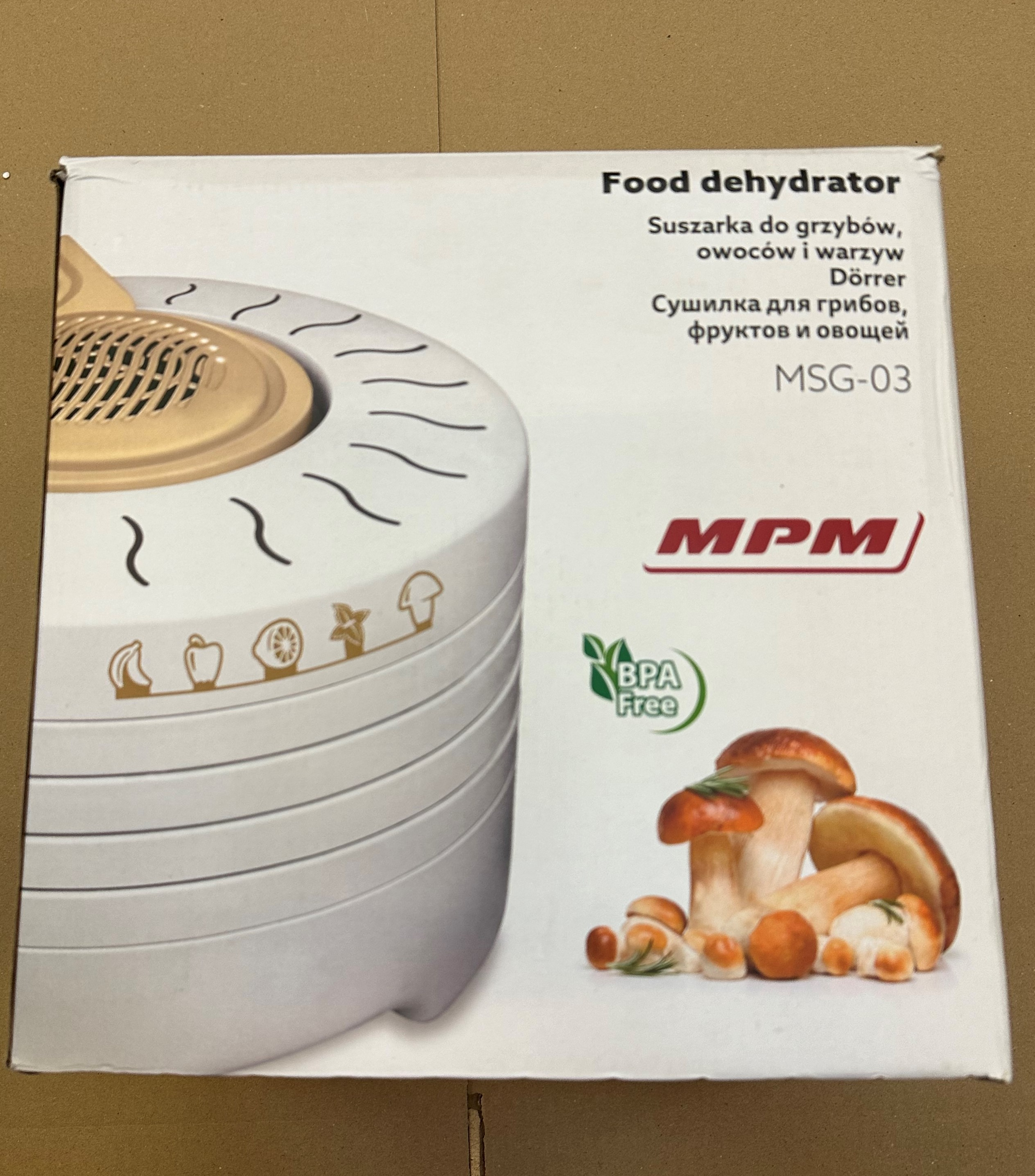 Pudełko dehydratora żywności z grzybami i tekstem w kilku językach. Biały i złoty.