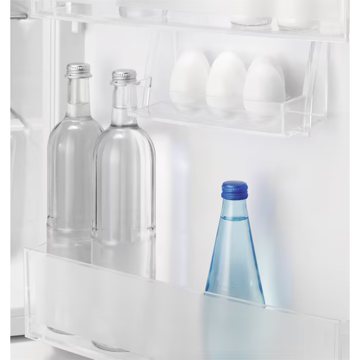 Kühlschrankinnenraum mit Wasserflaschen und Eiern. Eine Flasche mit blauem Deckel.