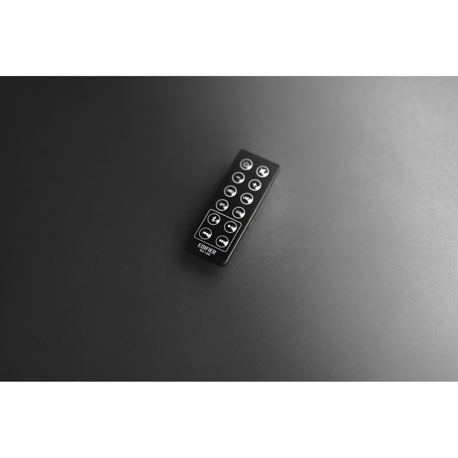 Un telecomando nero su una superficie scura. I pulsanti includono play, volume e altre funzioni.