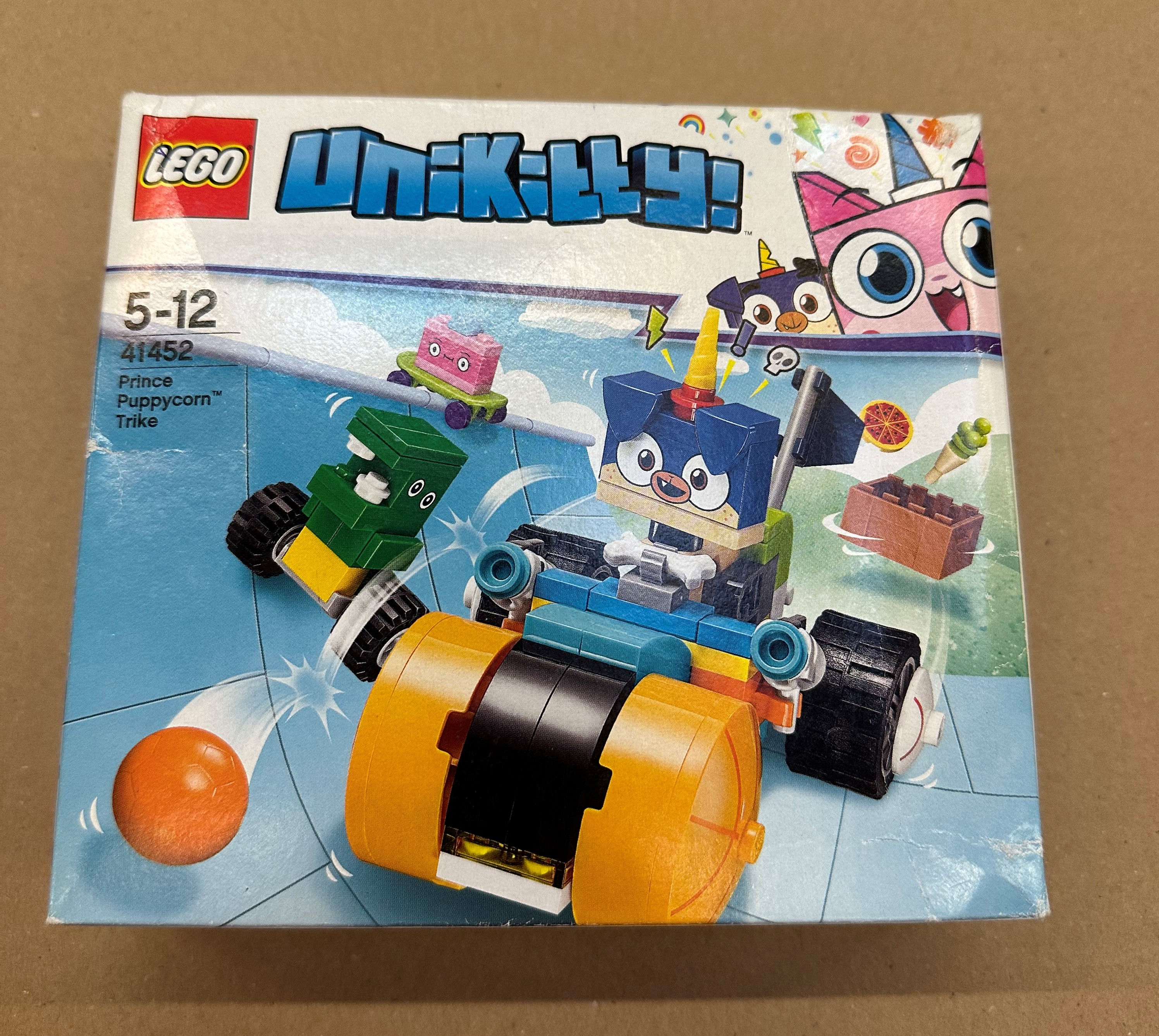 Pudełko Lego Unikitty Prince Puppycorn Trike z figurkami: niebieski pies, zielone pudełko, różowy sześcian.