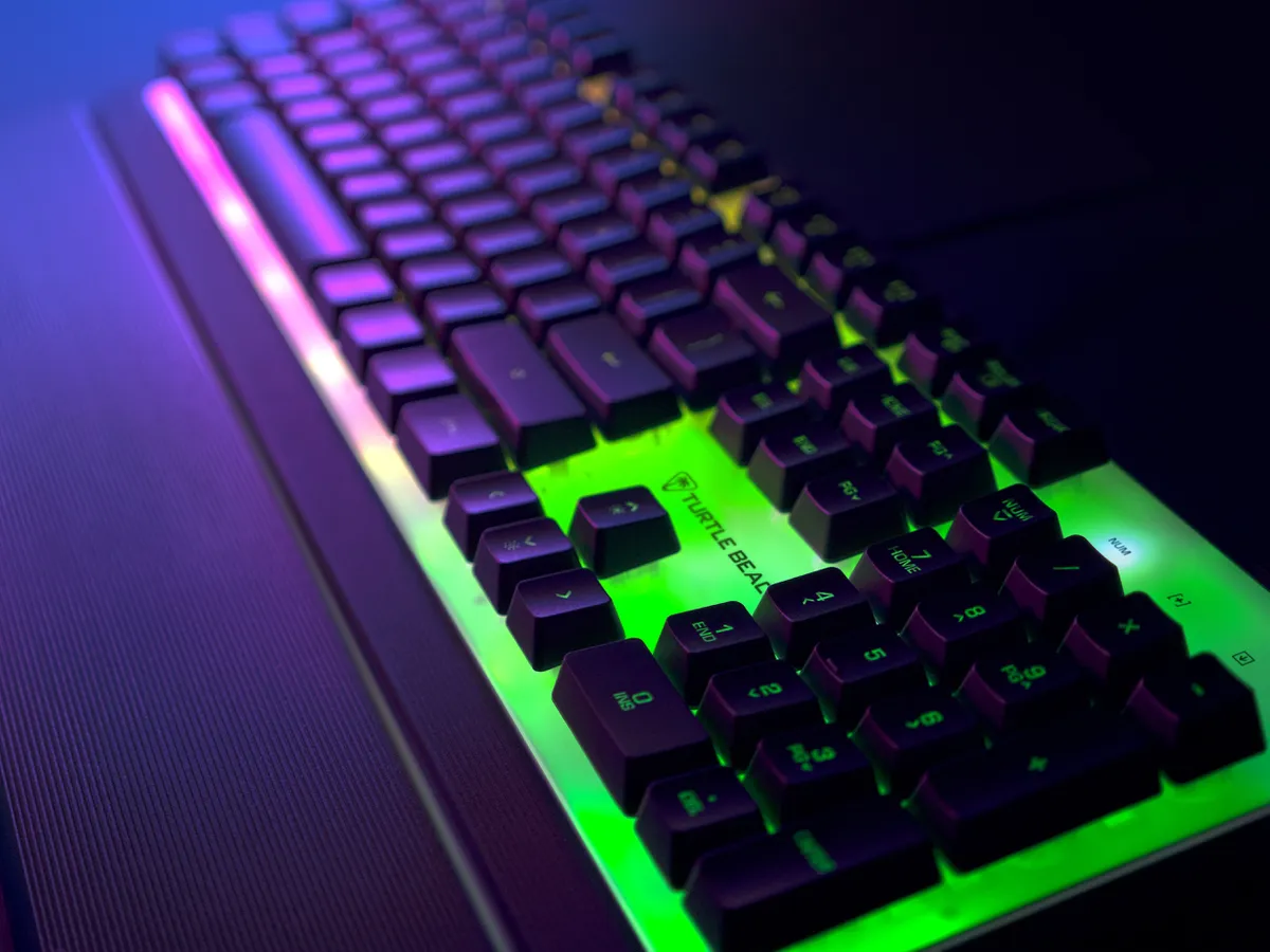 Eine Tastatur mit bunten Lichtern unter den Tasten. Die Tasten sind schwarz mit grünem und lila Licht.