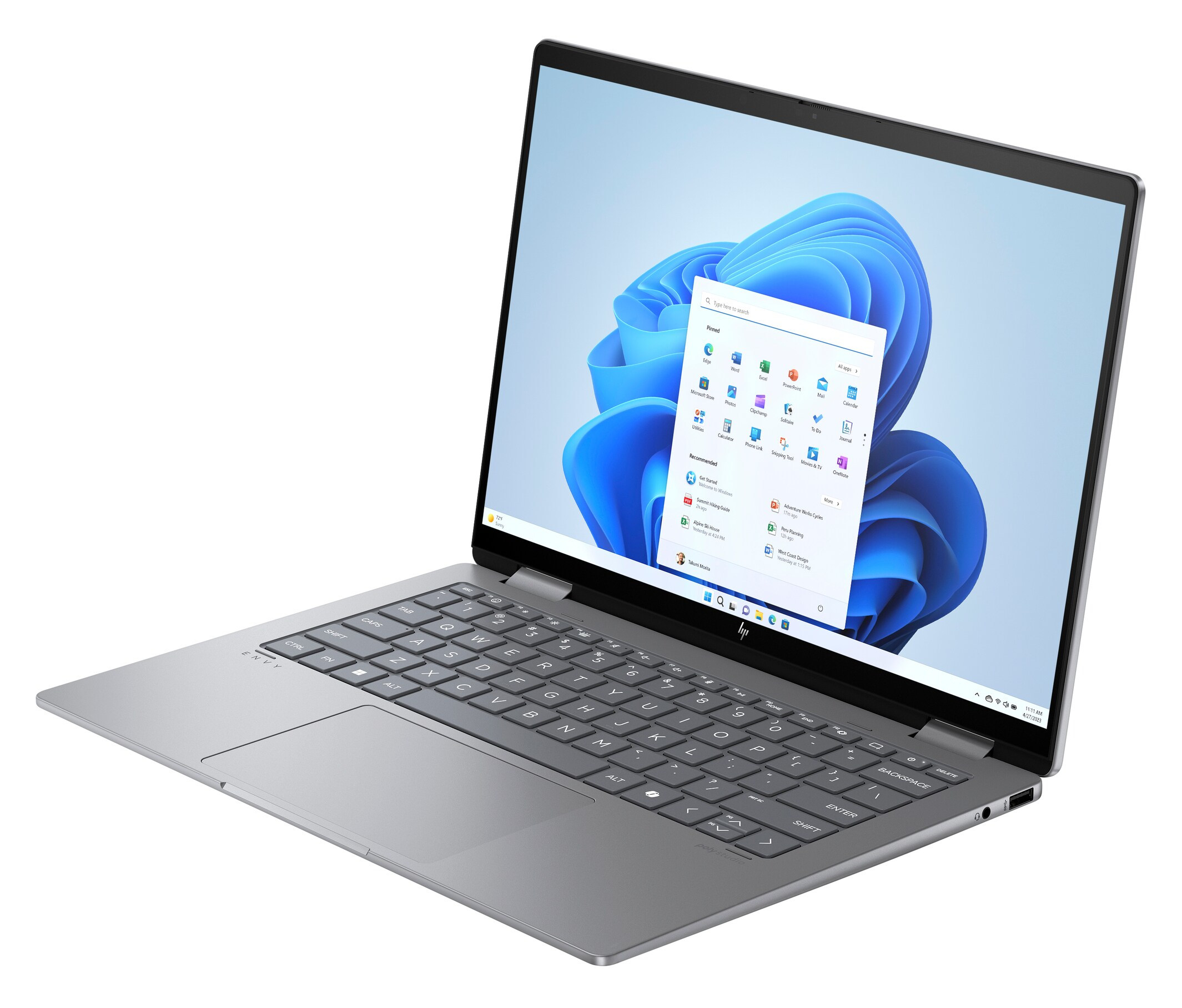 Szary laptop otwarty, wyświetlający interfejs Windows 11, ustawiony pod kątem na białej powierzchni.