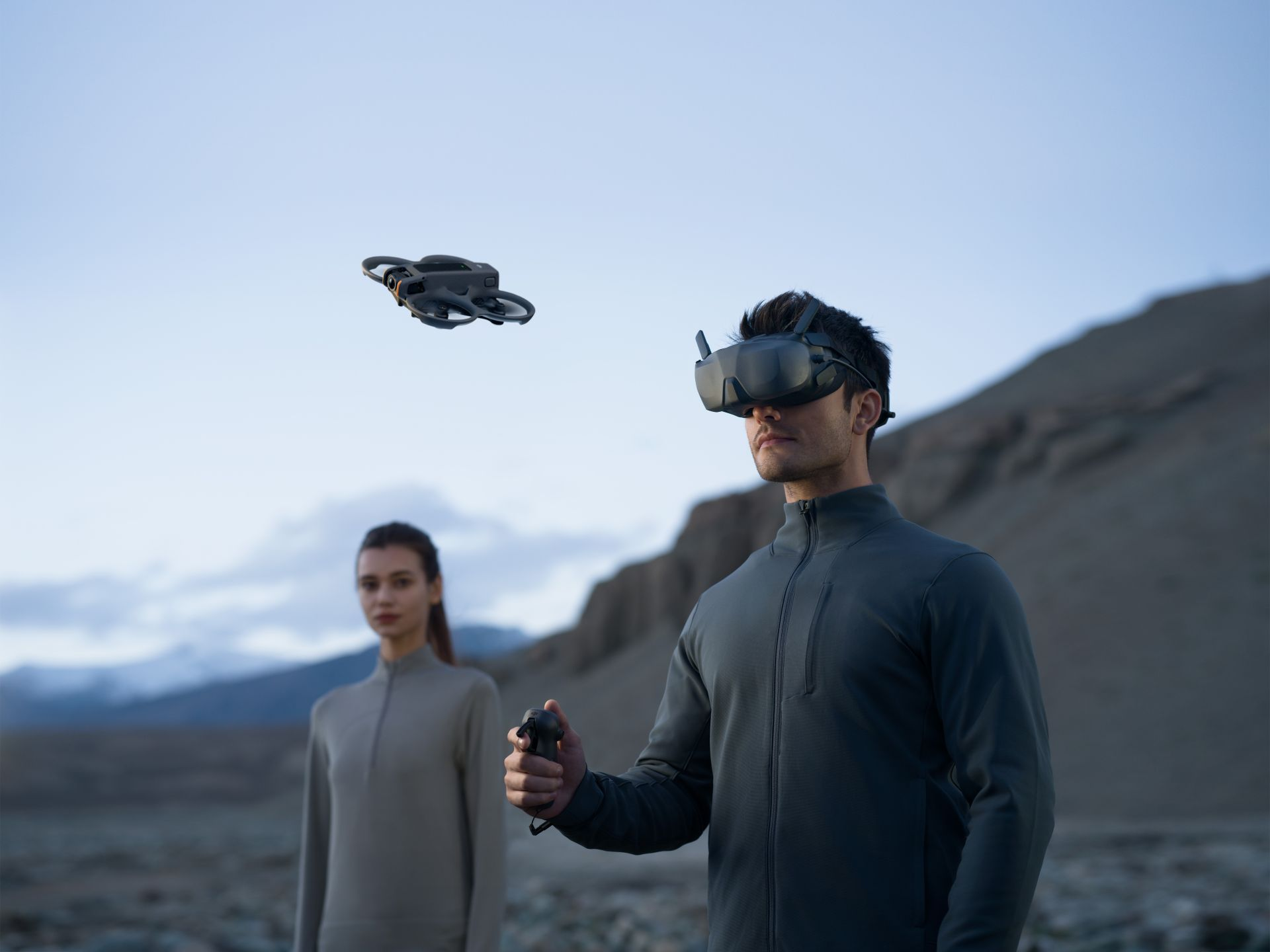 Person mit VR-Brille steuert eine Drohne, die über einer bergigen Landschaft fliegt.
