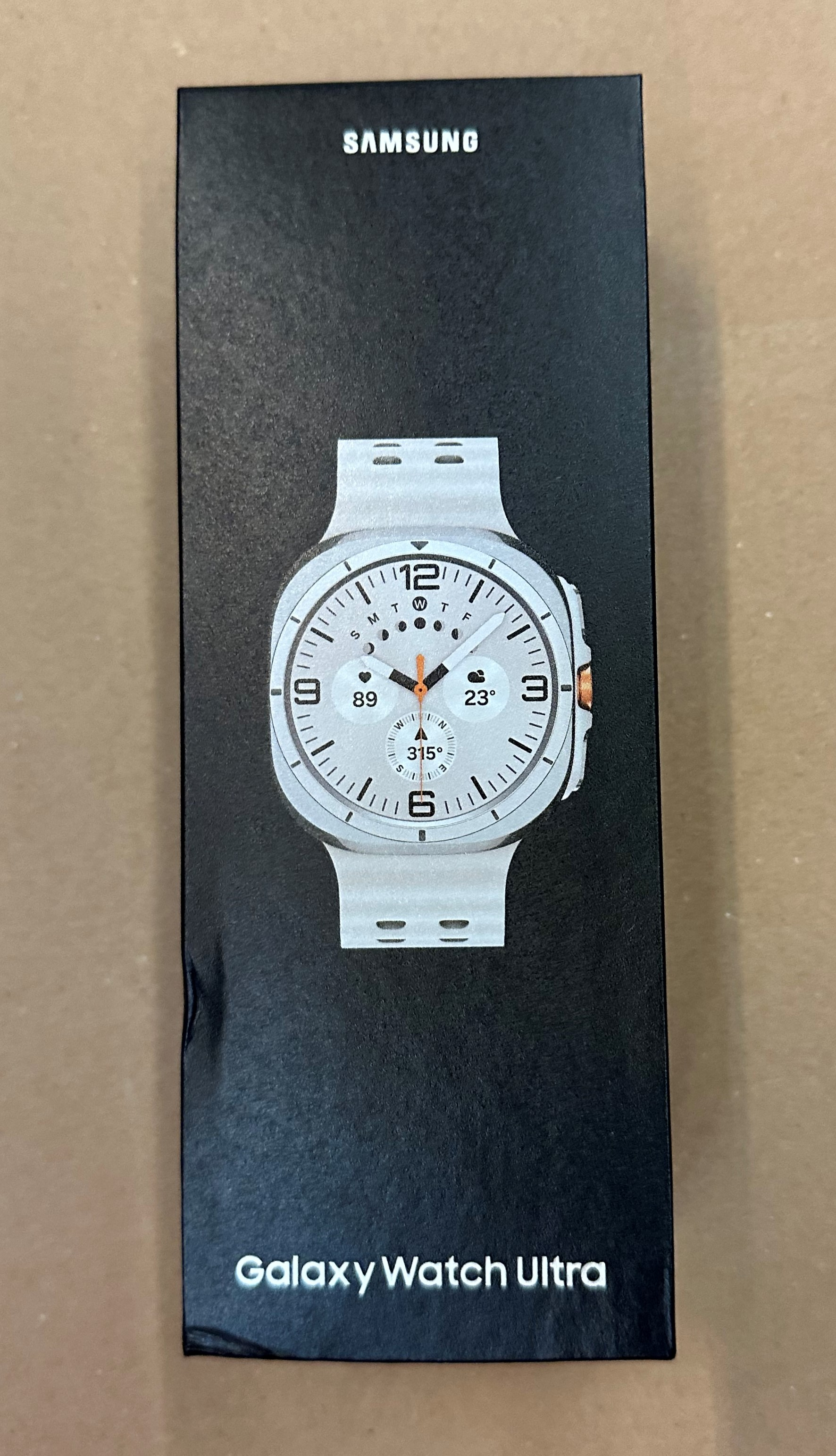 Czarne pudełko z białym Galaxy Watch Ultra, pokazujące jego tarczę.