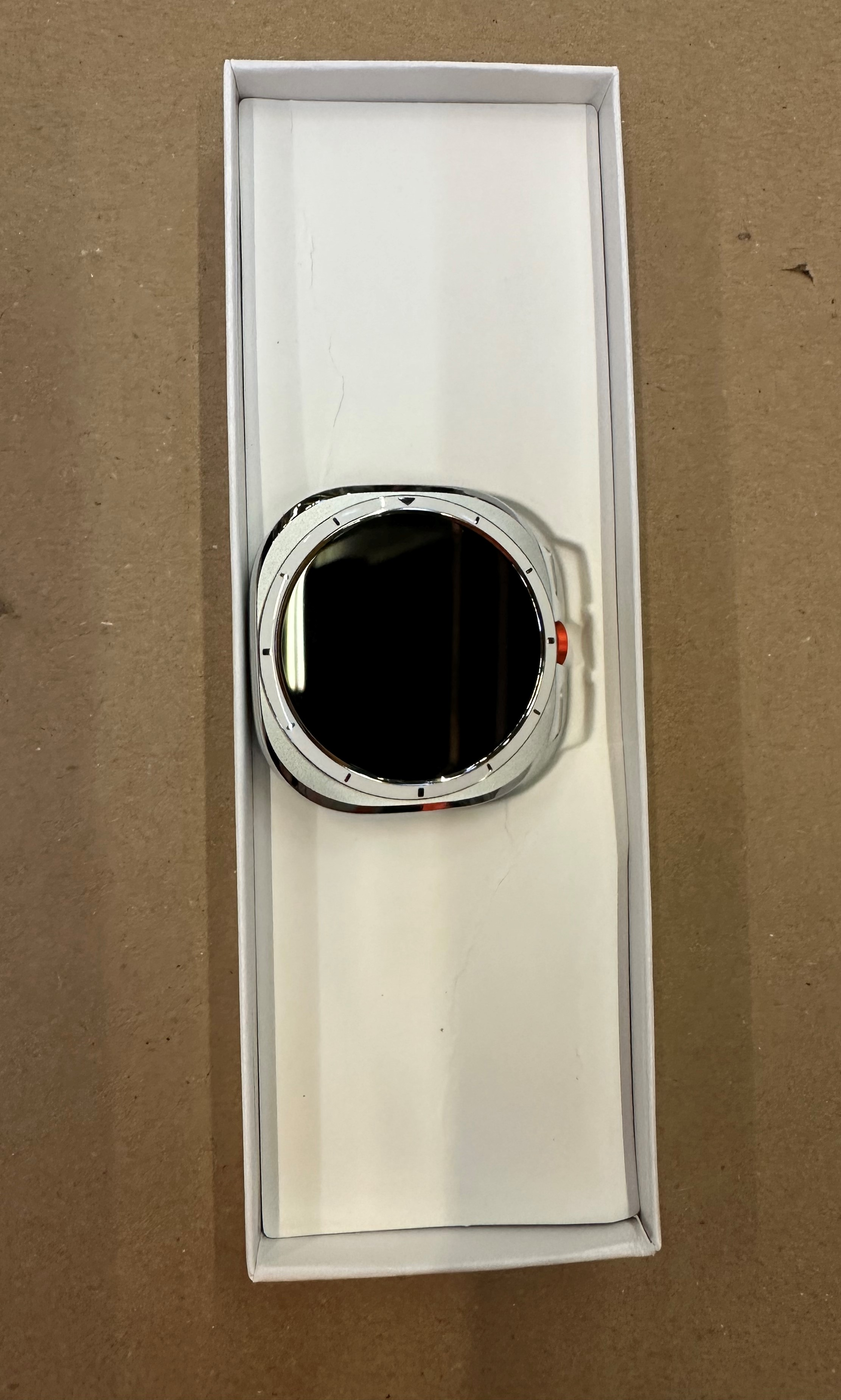 Smartwatch w białym pudełku. Czarny ekran, białe i czerwone detale oraz srebrna ramka.