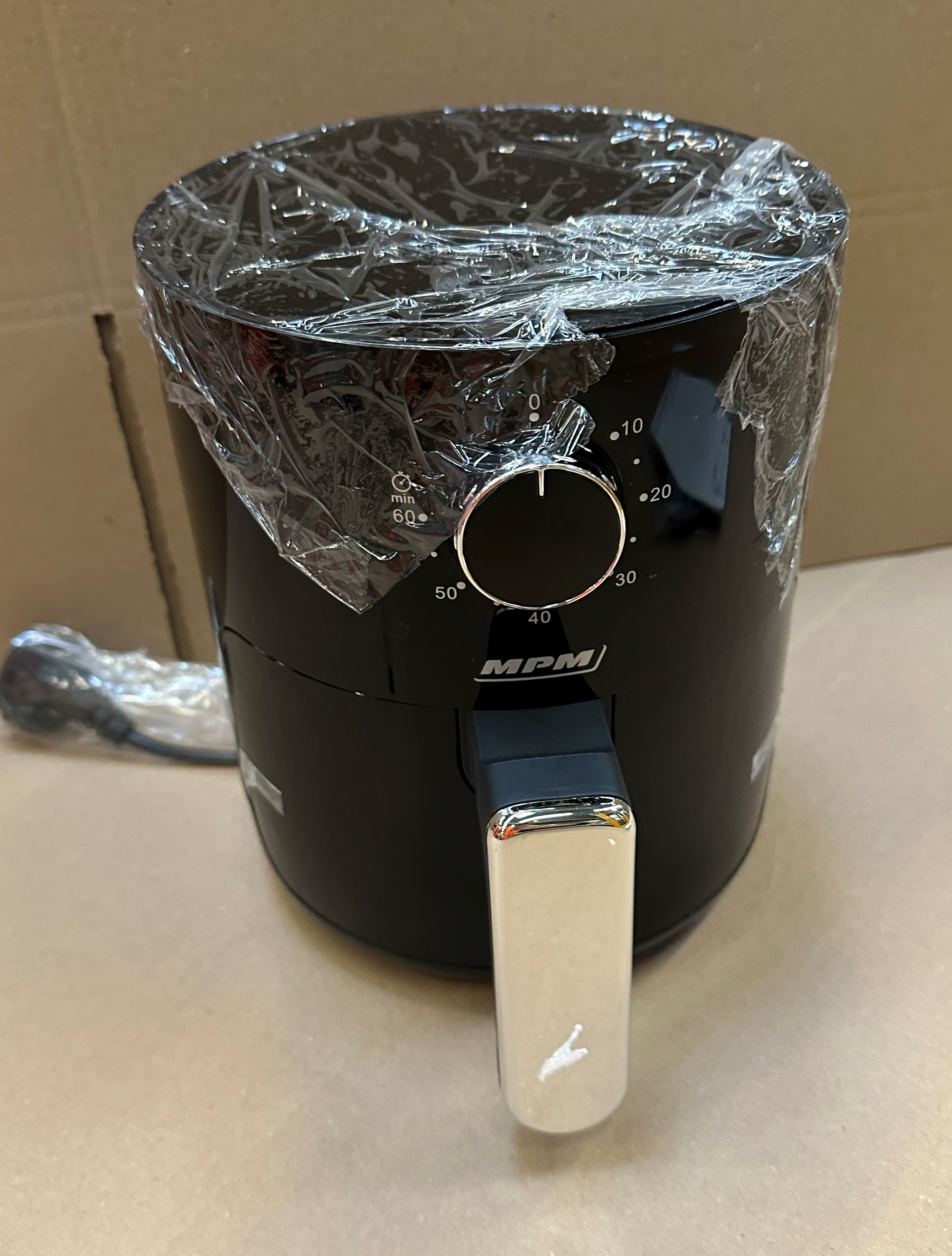 Czarna frytkownica powietrzna z uchwytem i pokrętłem. Zapakowana w plastik.