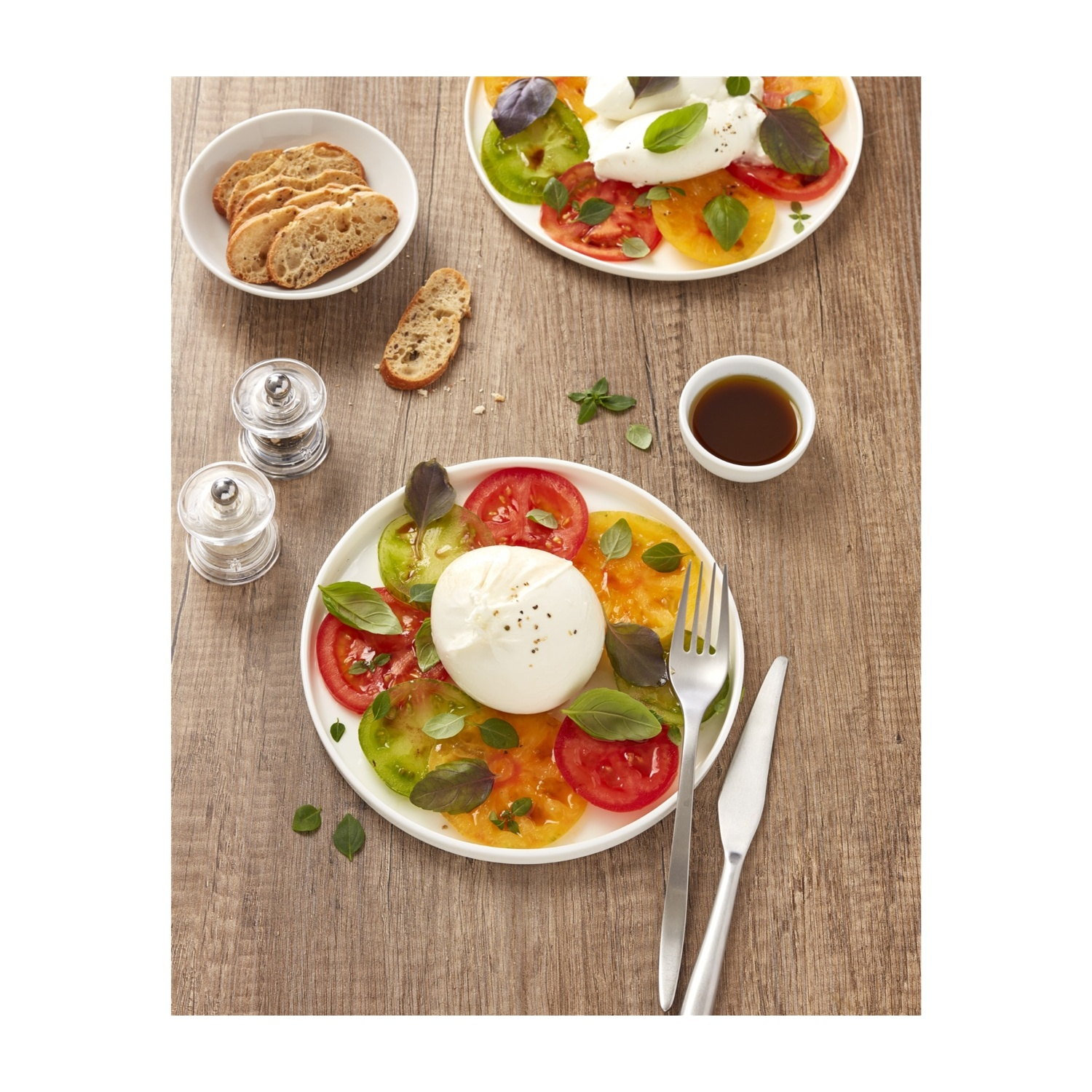 Un piatto di pomodori, mozzarella e basilico, più pane.