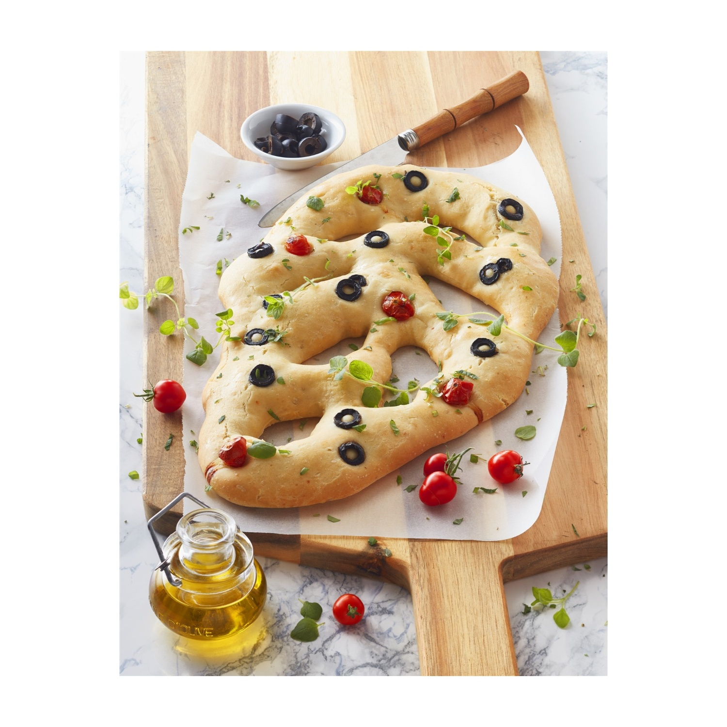 Pane artigianale con olive e pomodori su tagliere in legno con olio d'oliva.