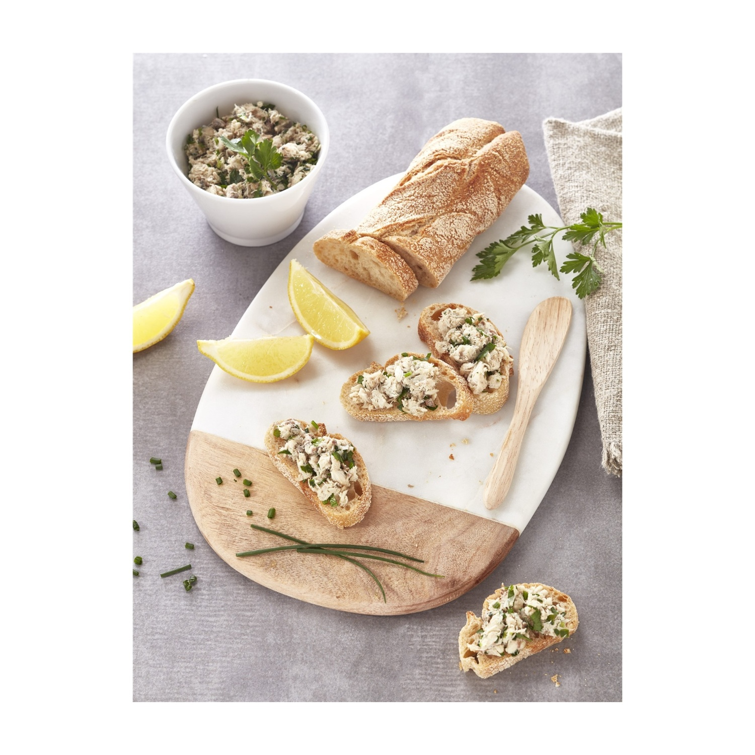 Presentazione di cibo: fette di pane con condimento, ciotola di mix, fette di limone e prezzemolo.