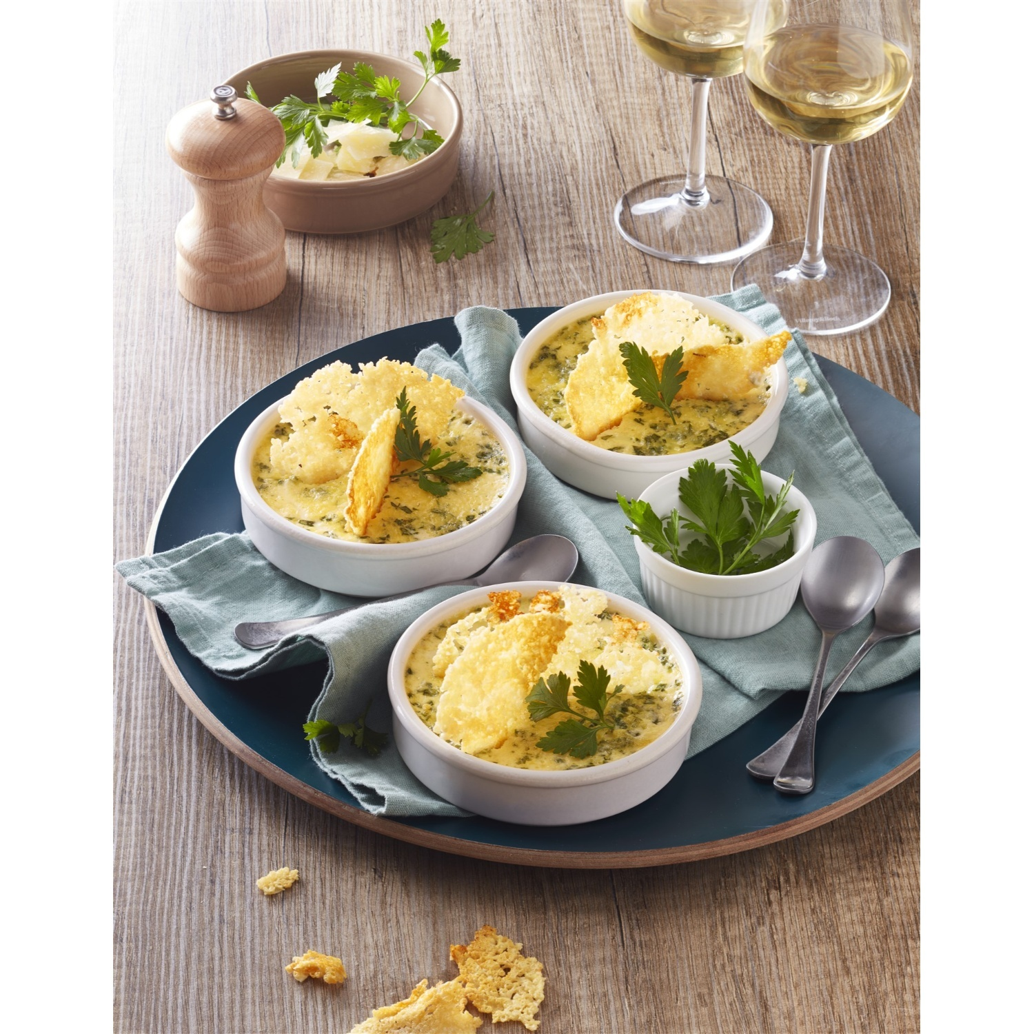 Tre ciotole di zuppa con crostini di formaggio e prezzemolo su un piatto.