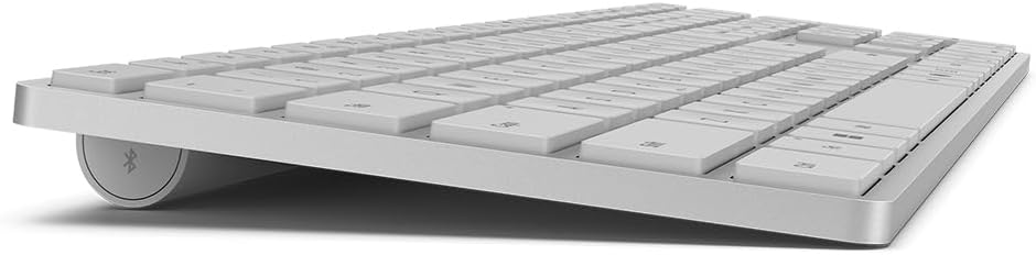 Un teclado plateado con teclas blancas. Se muestra en ángulo. Tiene un símbolo de Bluetooth.