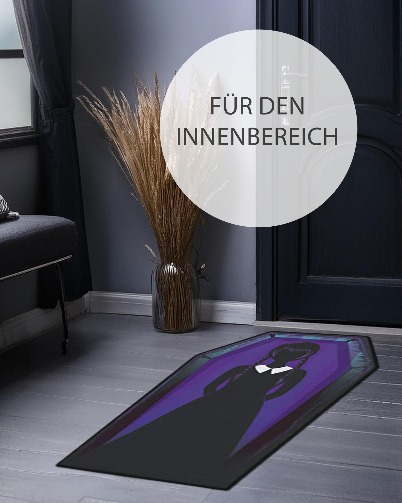 Eine Sargförmige Fußmatte mit der Silhouette einer Frau in einem schwarzen Kleid.