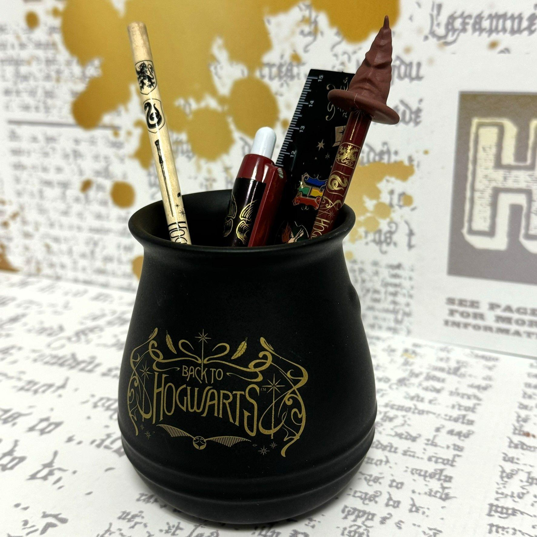 Schwarzer kesselartiger Topf mit Bleistiften und Lineal, beschriftet "Back to Hogwarts". Goldakzente.