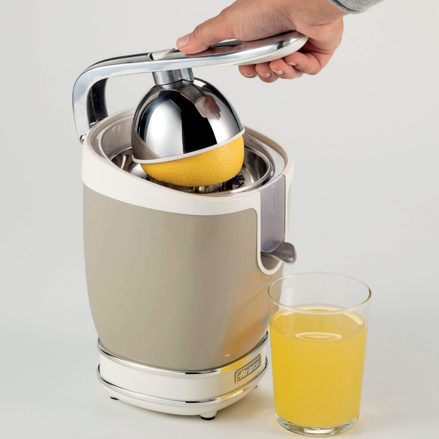 Spremiagrumi con un limone in fase di spremitura. Un bicchiere di succo accanto.