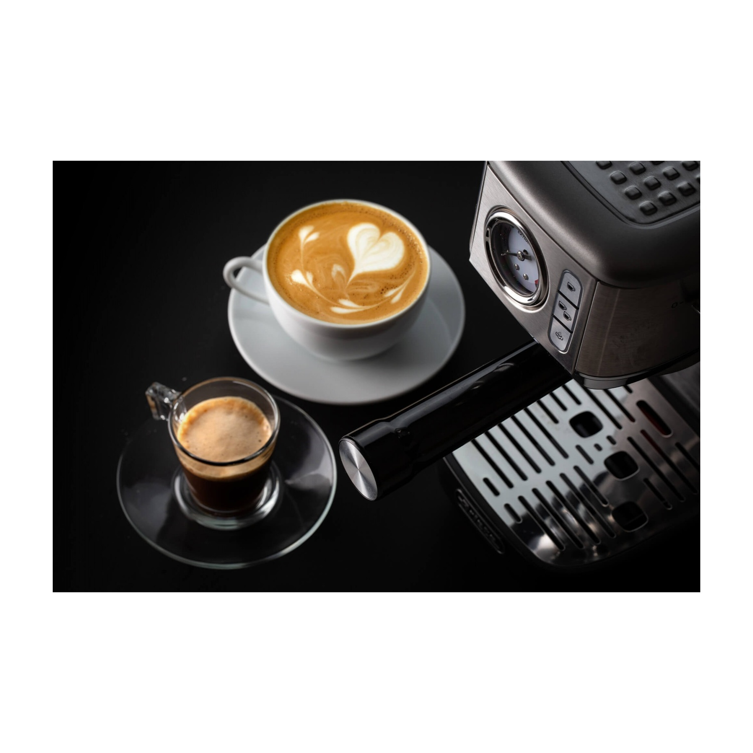 Macchina per caffè con caffè, latte art e un bicchiere di espresso trasparente su una superficie nera.
