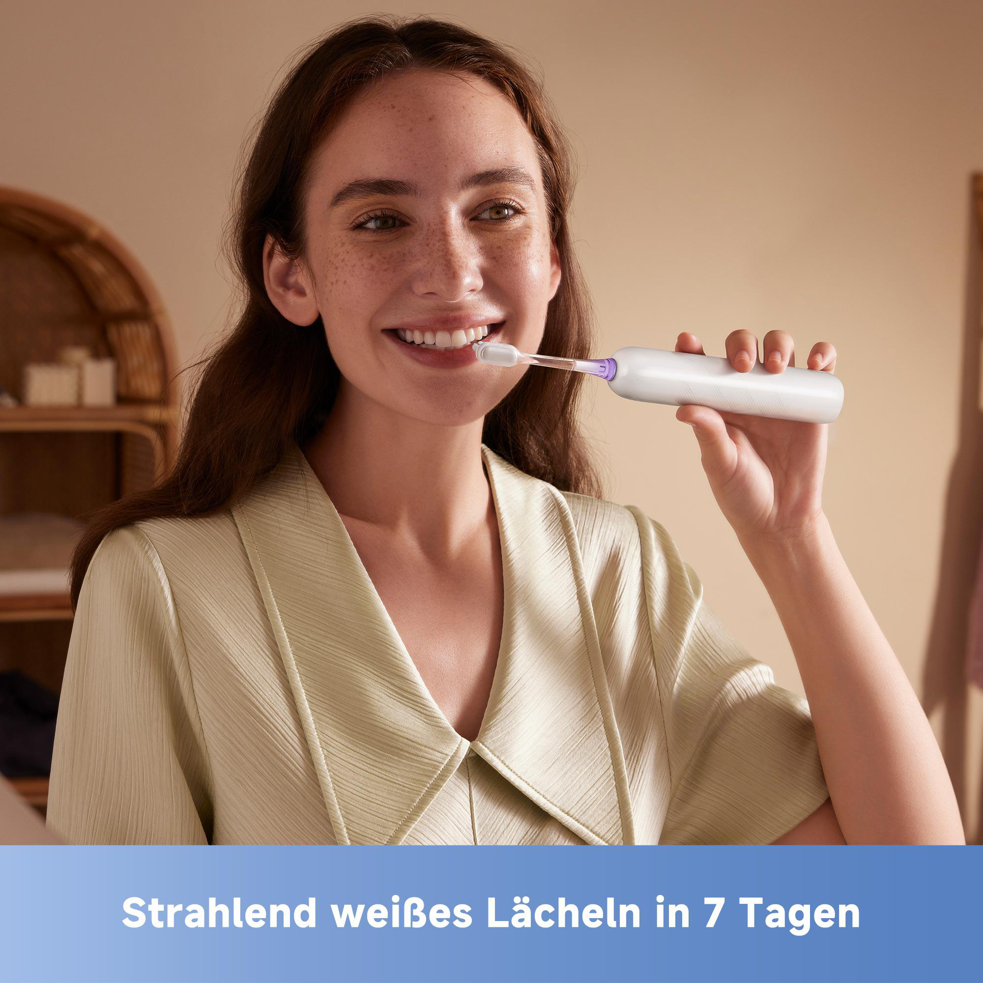 Frau lächelt, während sie sich mit einer elektrischen Zahnbürste die Zähne putzt, im Badezimmer.