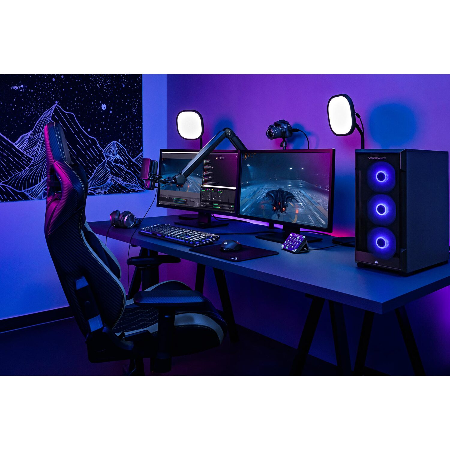Gaming setup with two monitors, a PC, and accessories, under blue light.