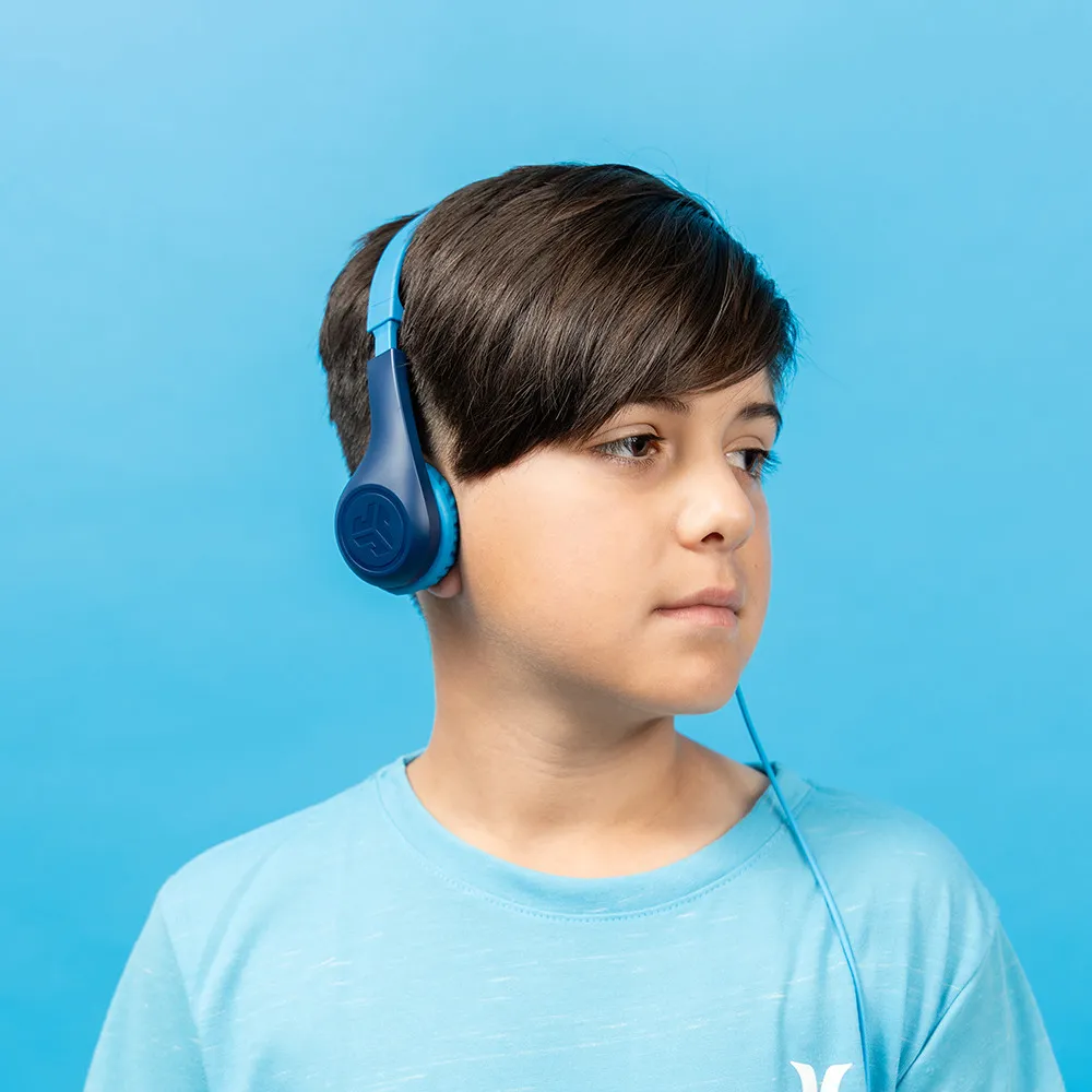 Ragazzo con cuffie blu, guarda di lato, su sfondo blu.