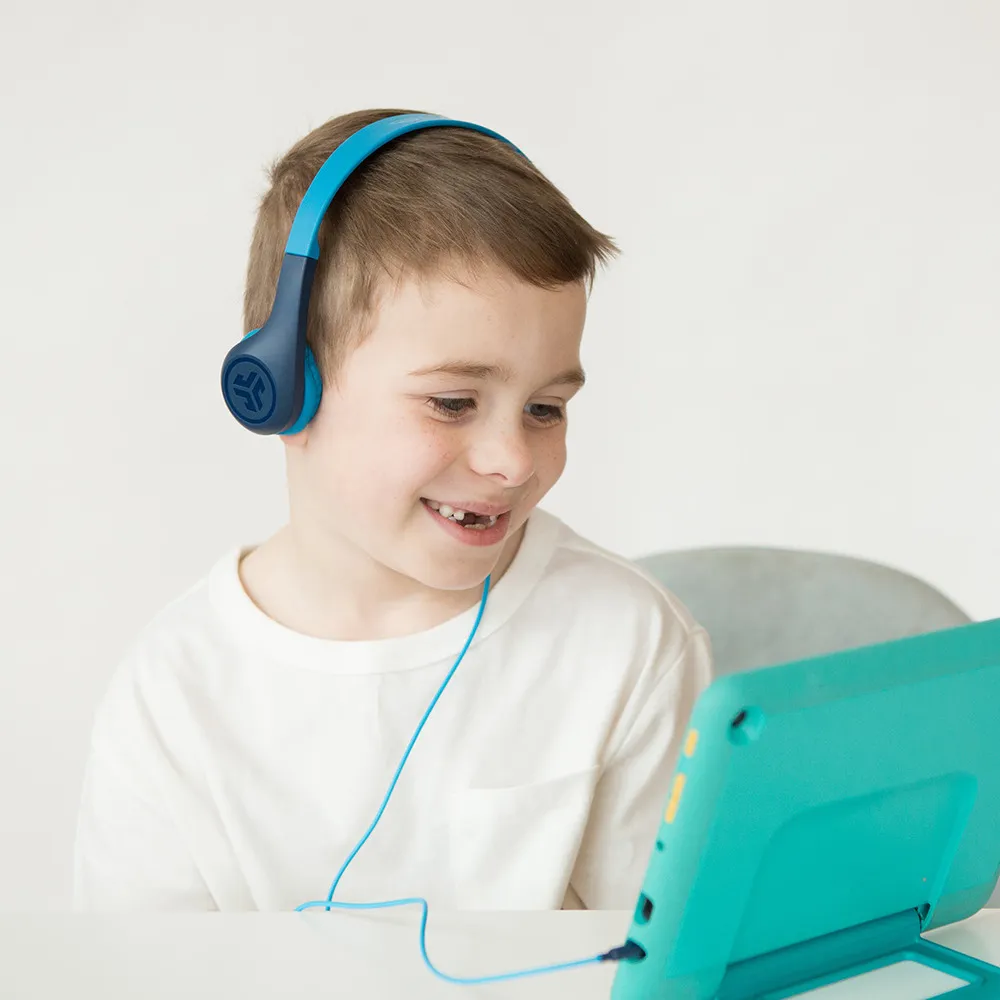 Un ragazzo con cuffie blu guarda un tablet turchese.