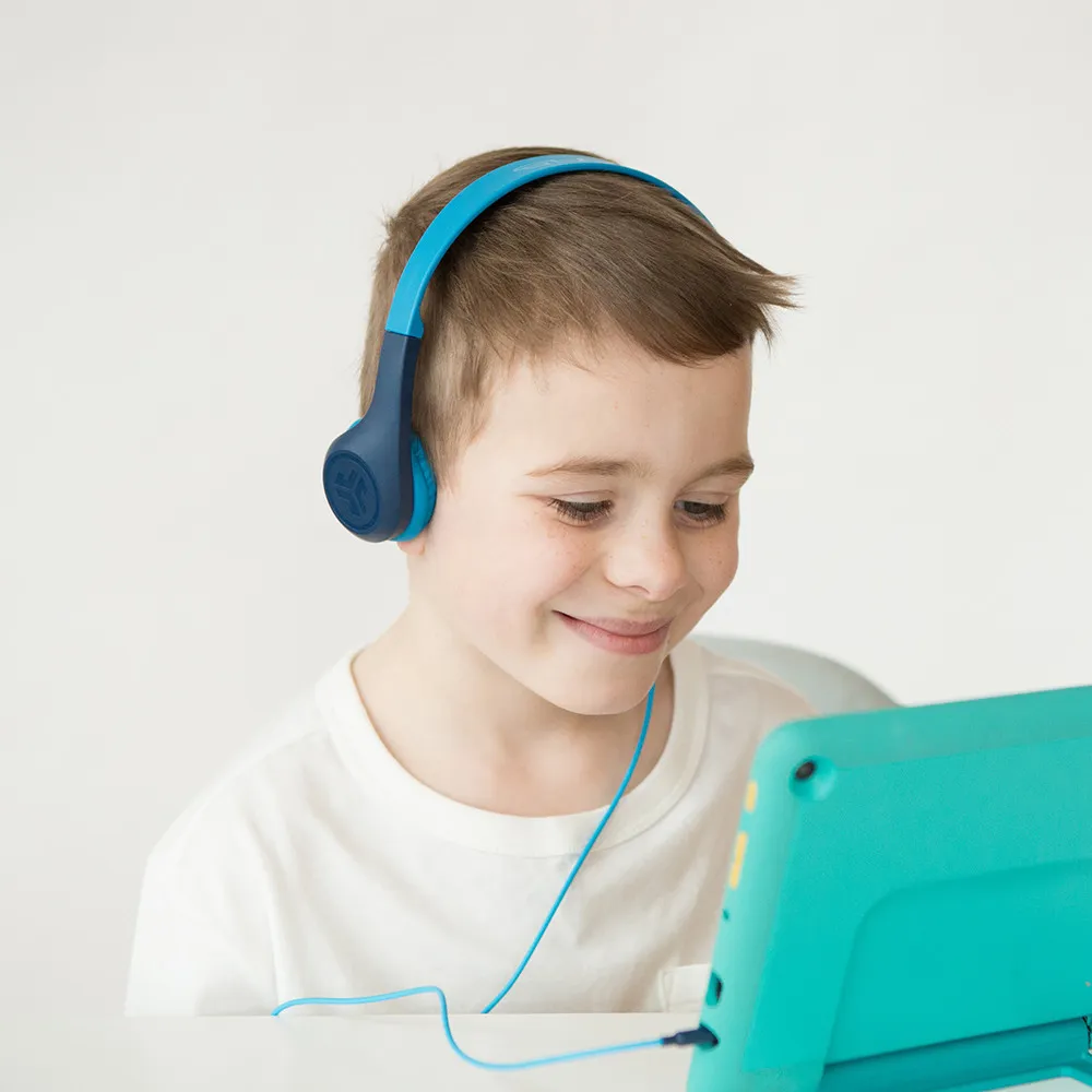 Un ragazzino con cuffie blu, guarda lo schermo di un tablet.