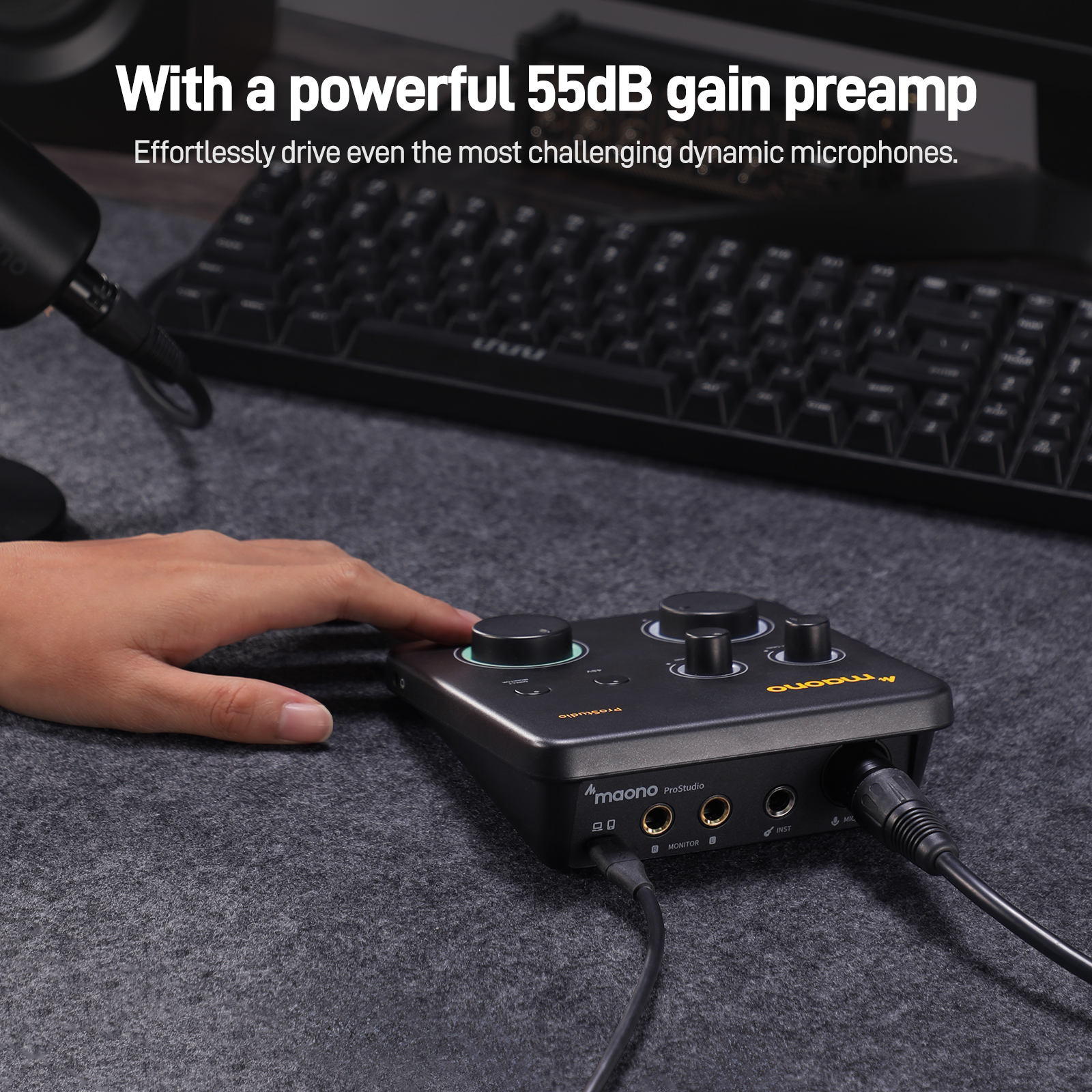 Une interface audio noire avec des boutons et des ports, et une main en train d'en régler un. Fond gris.