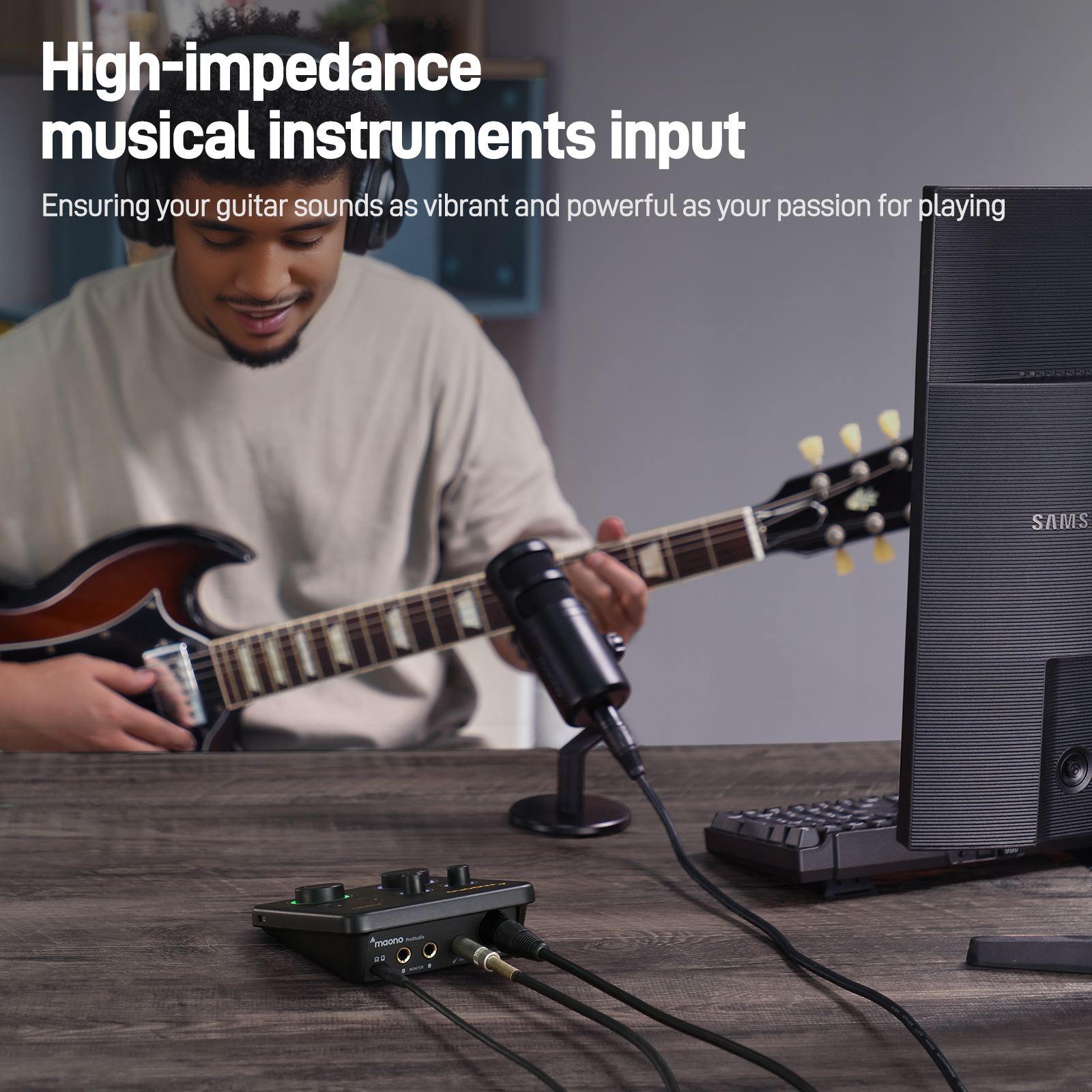 Homme jouant de la guitare avec un microphone et une interface audio. Écran d'ordinateur visible.