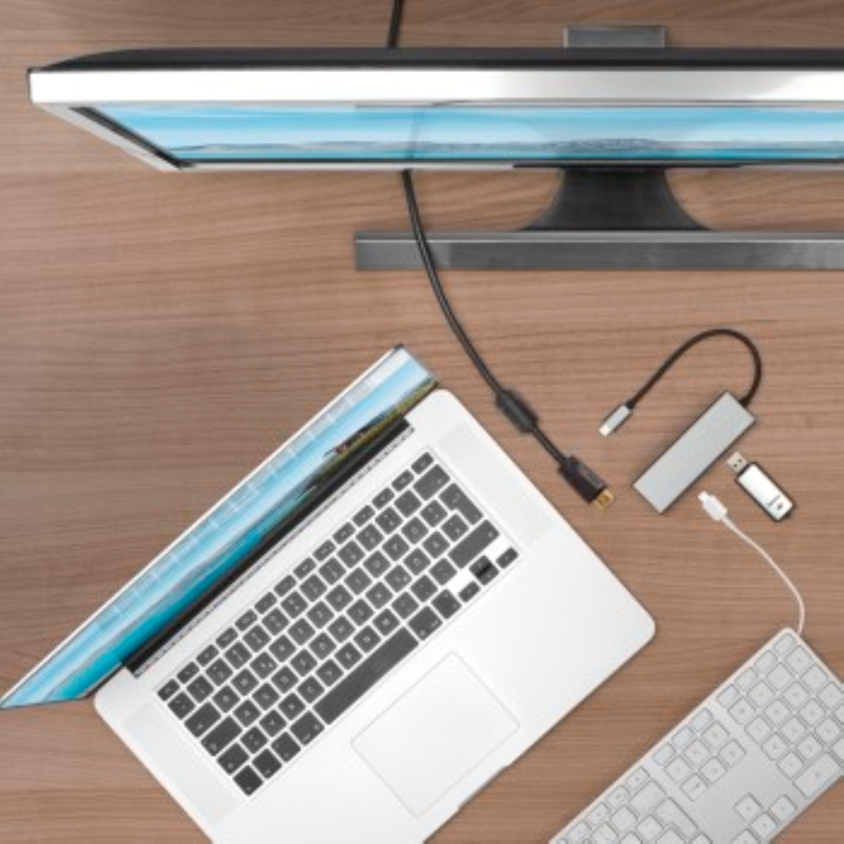Ahşap bir masada dizüstü bilgisayar, monitör, klavye ve USB hub. Hepsi birbirine bağlı.