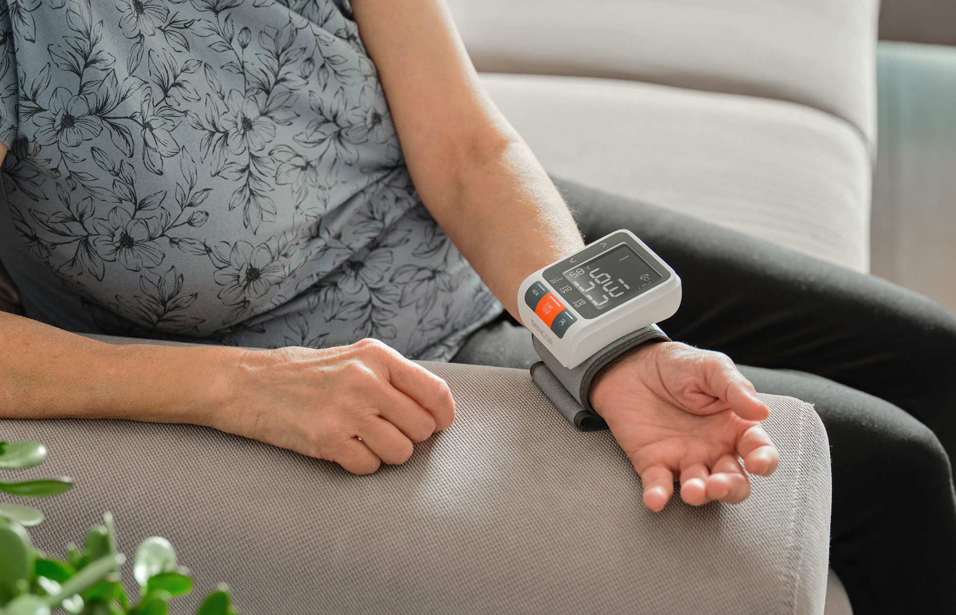 Osoba nosząca monitor ciśnienia krwi na nadgarstku. Ekran wyświetla liczby.