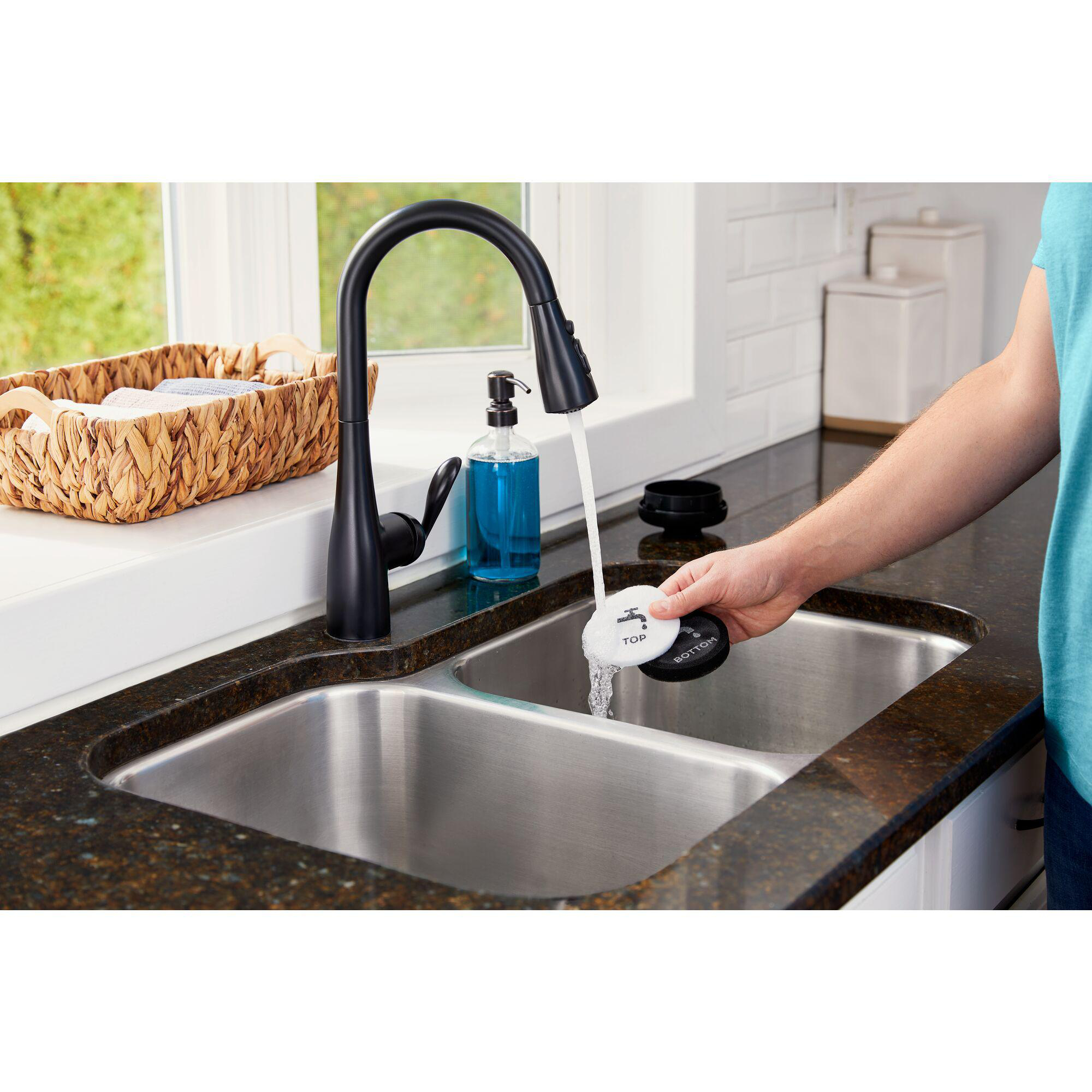 Eine Person benutzt einen Top/Bottom Wassertester an einem Küchenbecken.
