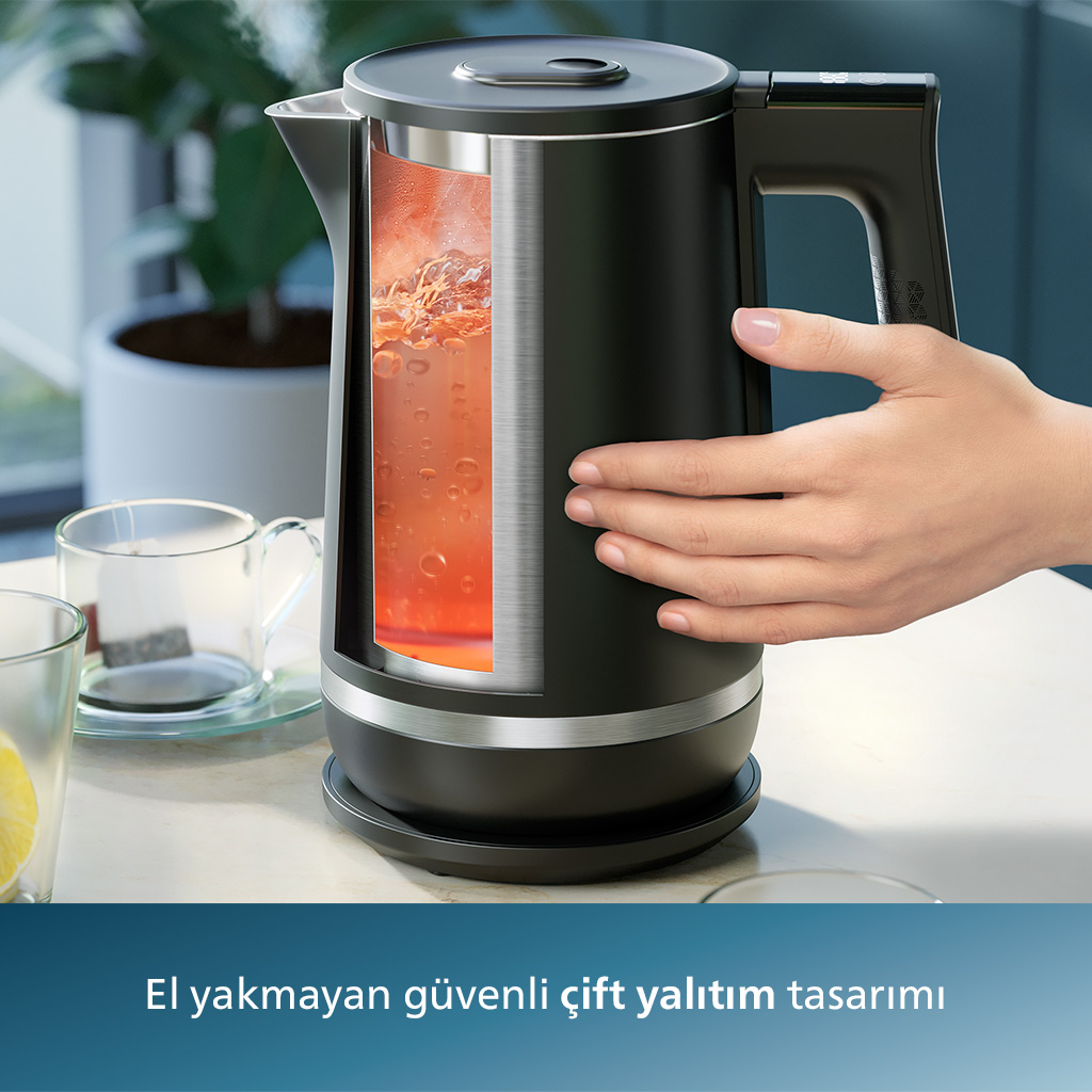 Sıcak kırmızı sıvı, el ve masa gösteren kesitli siyah su ısıtıcısı.