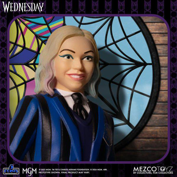 Eine Wednesday Addams-Figur lächelt. Sie trägt eine blau gestreifte Jacke. Der Hintergrund ist ein Buntglasfenster.