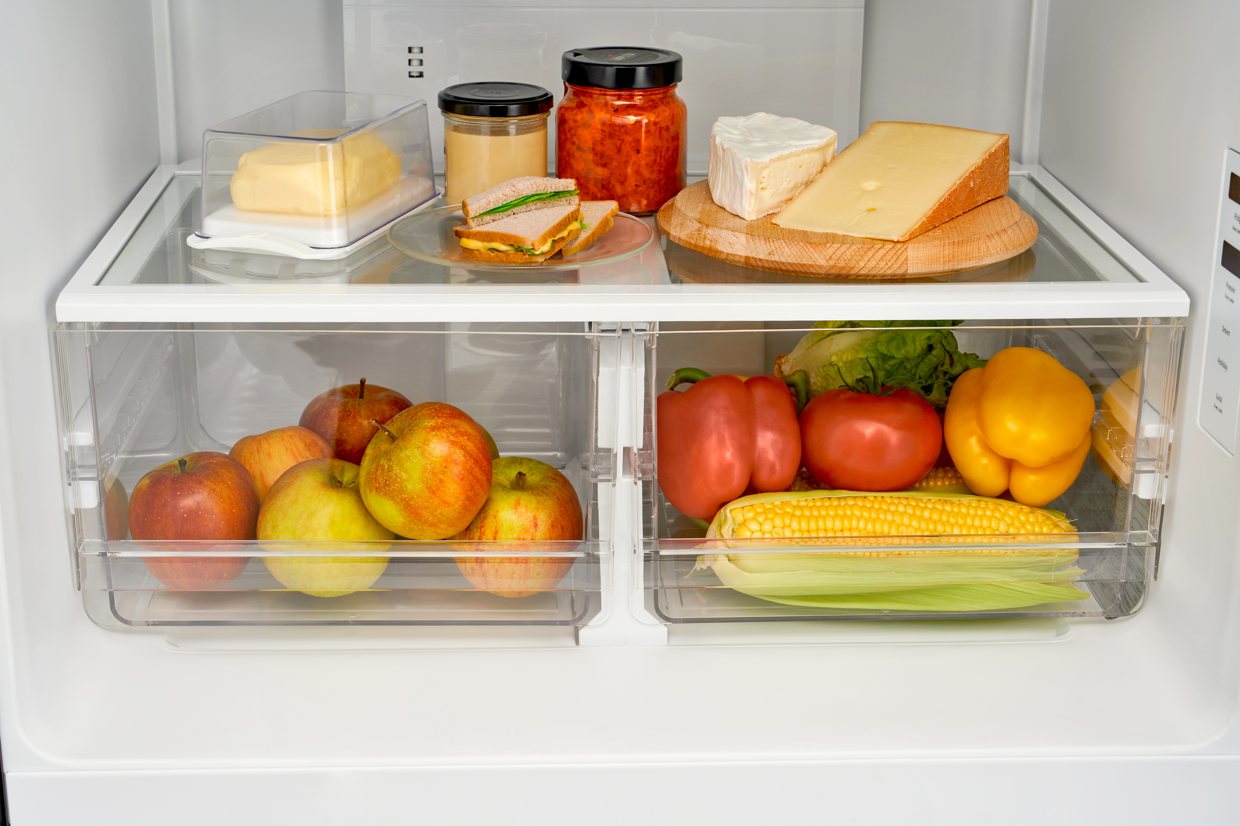 Kühlschrankinnenraum mit Lebensmitteln, Äpfel, Käse und Gemüse.
