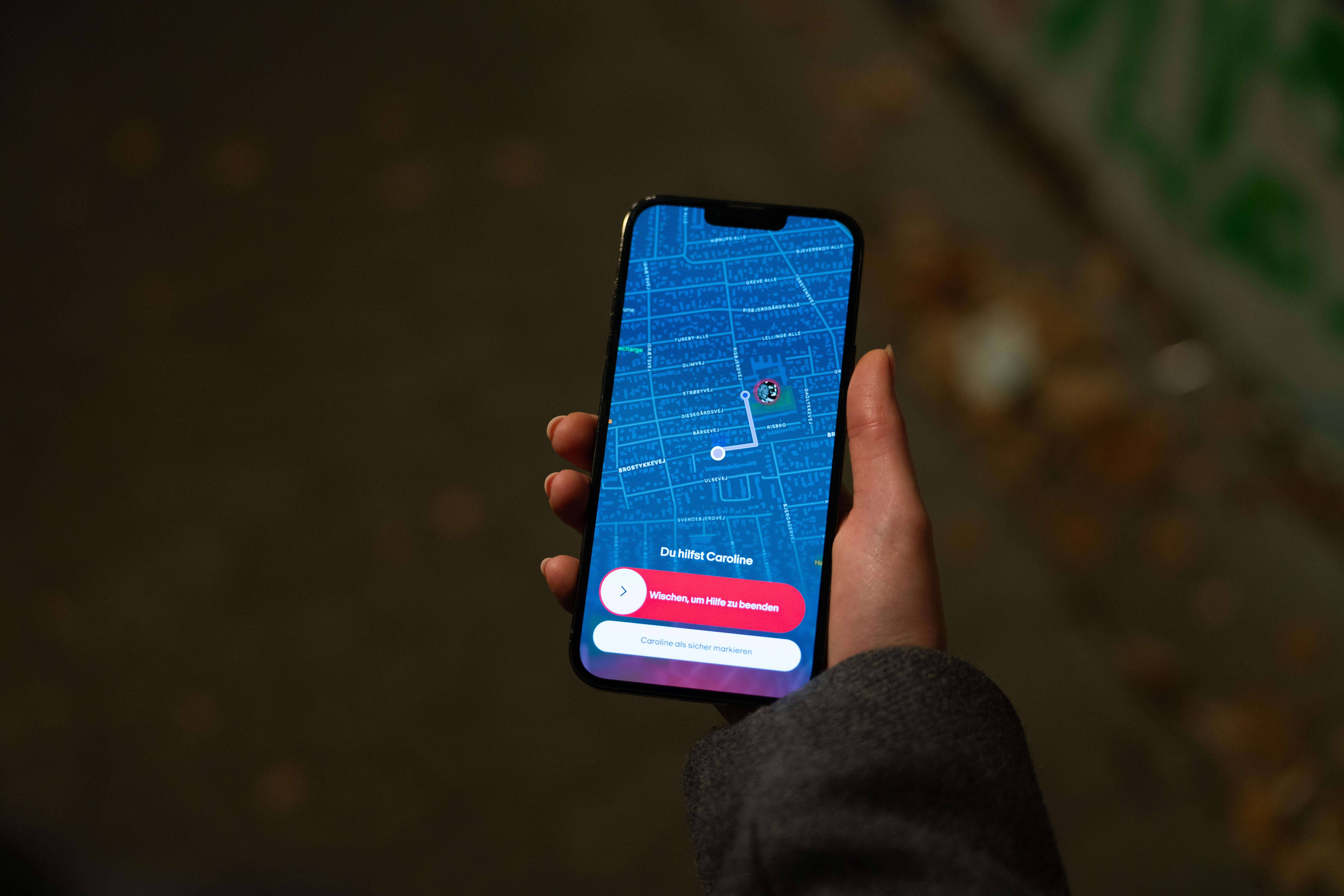 Eine Hand, die ein Smartphone hält, das eine Karte mit einer blauen Route und App-Oberfläche anzeigt.