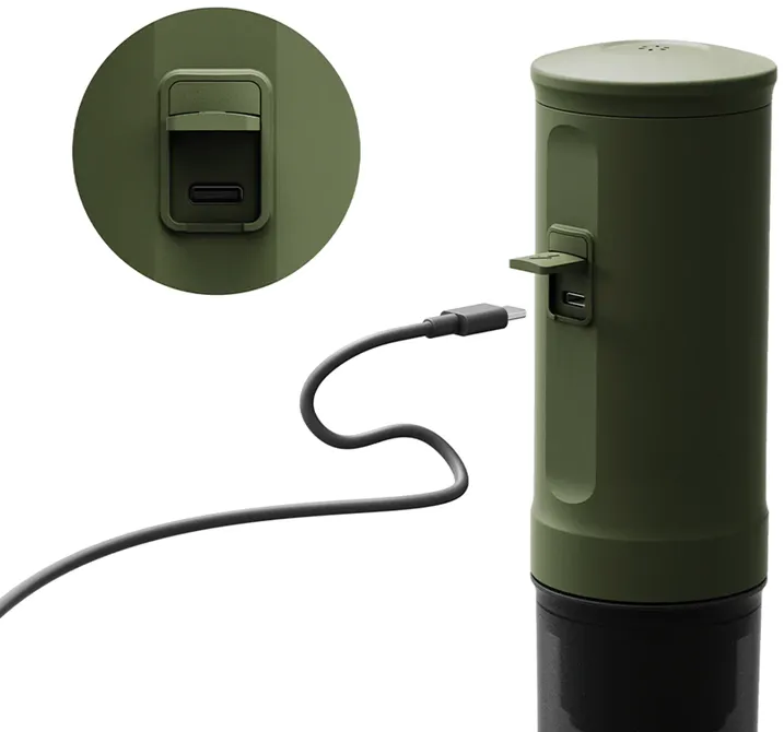 Egy zöld henger alakú eszköz USB porttal. Egy fekete töltőkábel csatlakozik.
