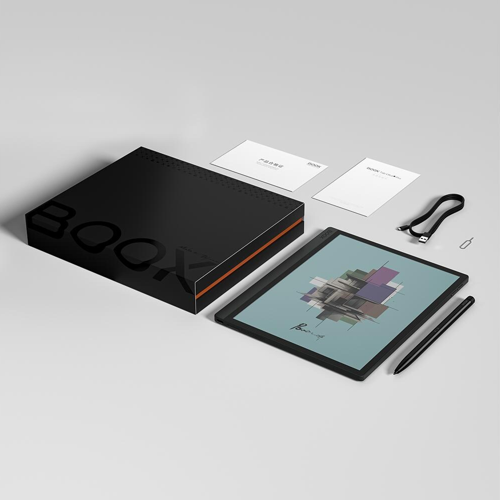 Liseuse dans une boîte. Tablette noire avec un stylet, boîte avec du texte et des cartes sur une surface blanche.
