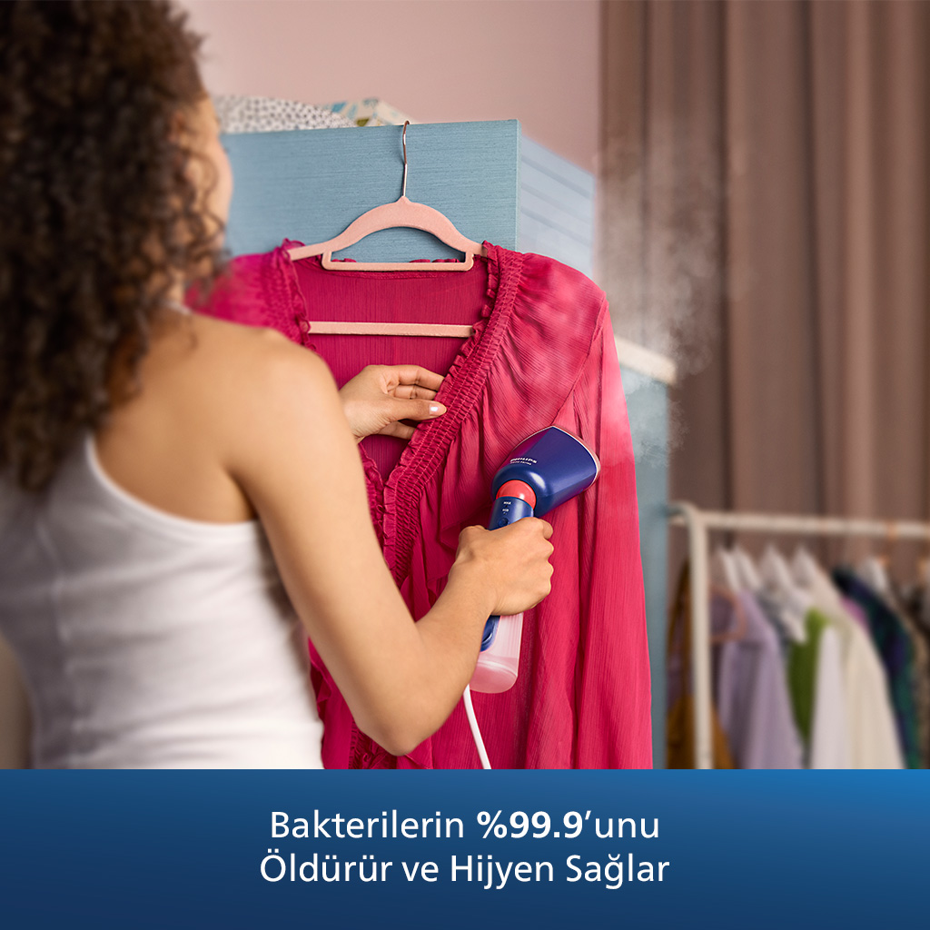 Bir kadın, pembe bir bluzu mavi bir buhar makinesiyle buharlıyor. Metin, “Bakterilerin %99,9'unu öldürür” diyor.
