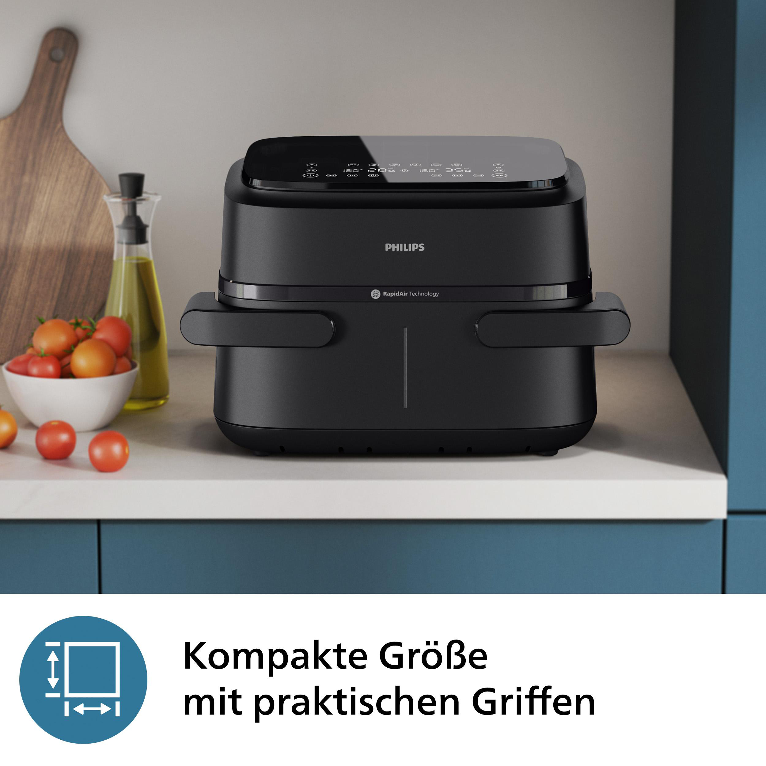 Ein schwarzer Philips-Heißluftfritteuse auf einer Theke mit Tomaten und einem Holzbrett.