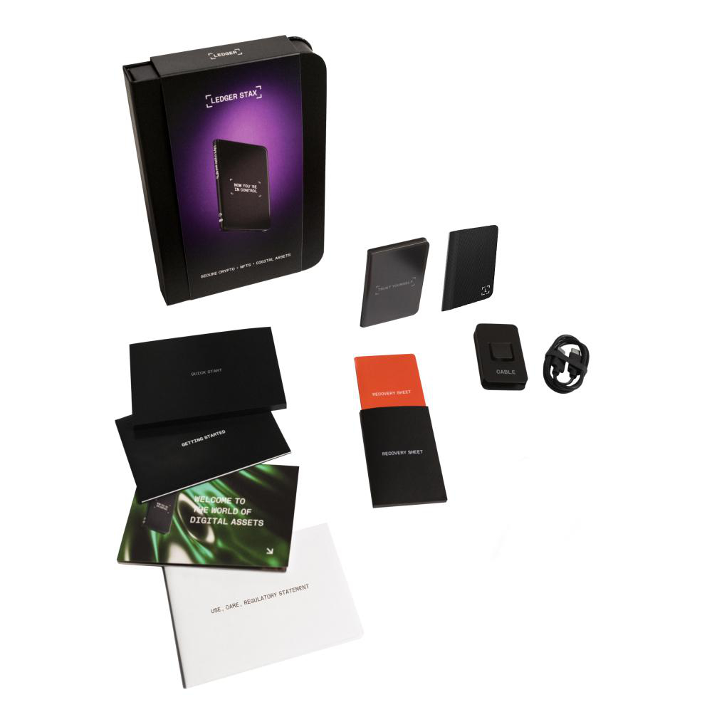 Geöffnete Ledger Stax Box mit Zubehör, darunter Karten, Kabel und ein schwarzes Gerät.