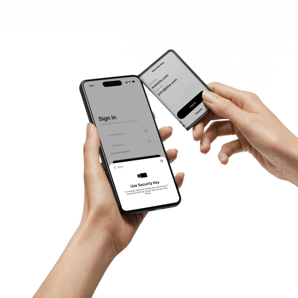 Hände halten ein Telefon und einen Sicherheitsschlüssel. Telefon zeigt Anmeldebildschirm.