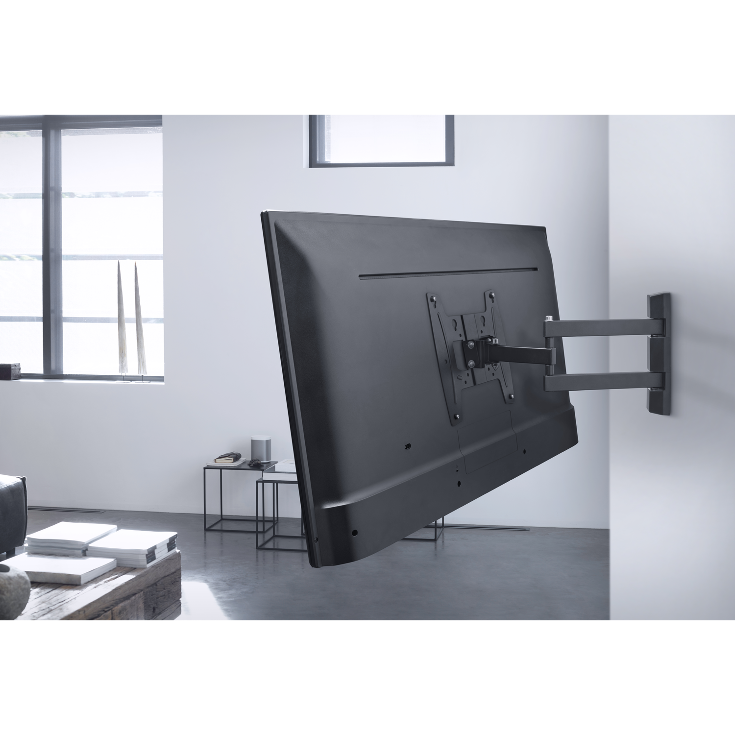 TV gemonteerd op een wandbeugel. Zwart scherm, zijaanzicht, witte kamer, ramen op de achtergrond.