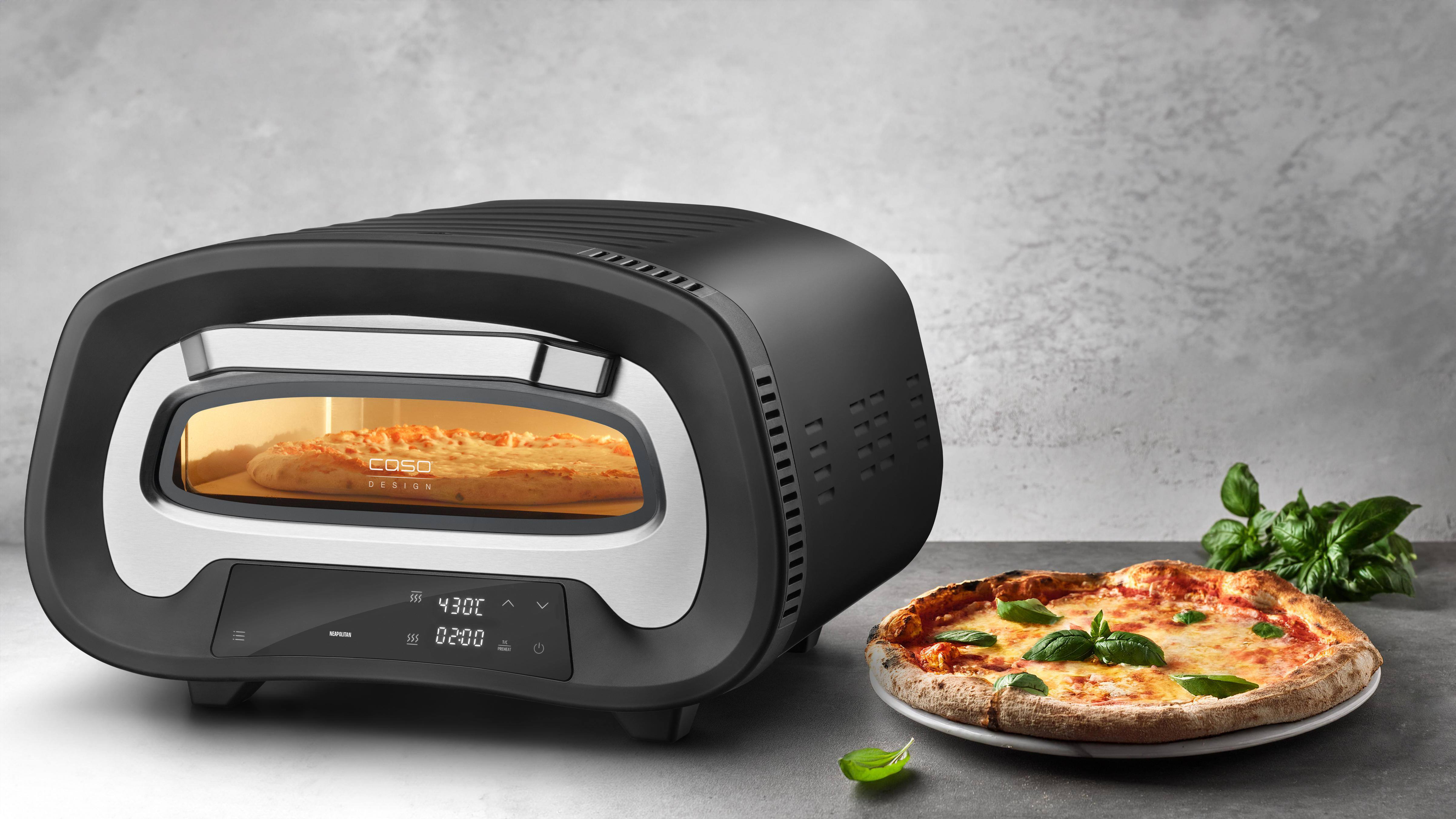 Schwarzer Pizzaofen mit Pizza im Inneren und fertiger Pizza rechts.