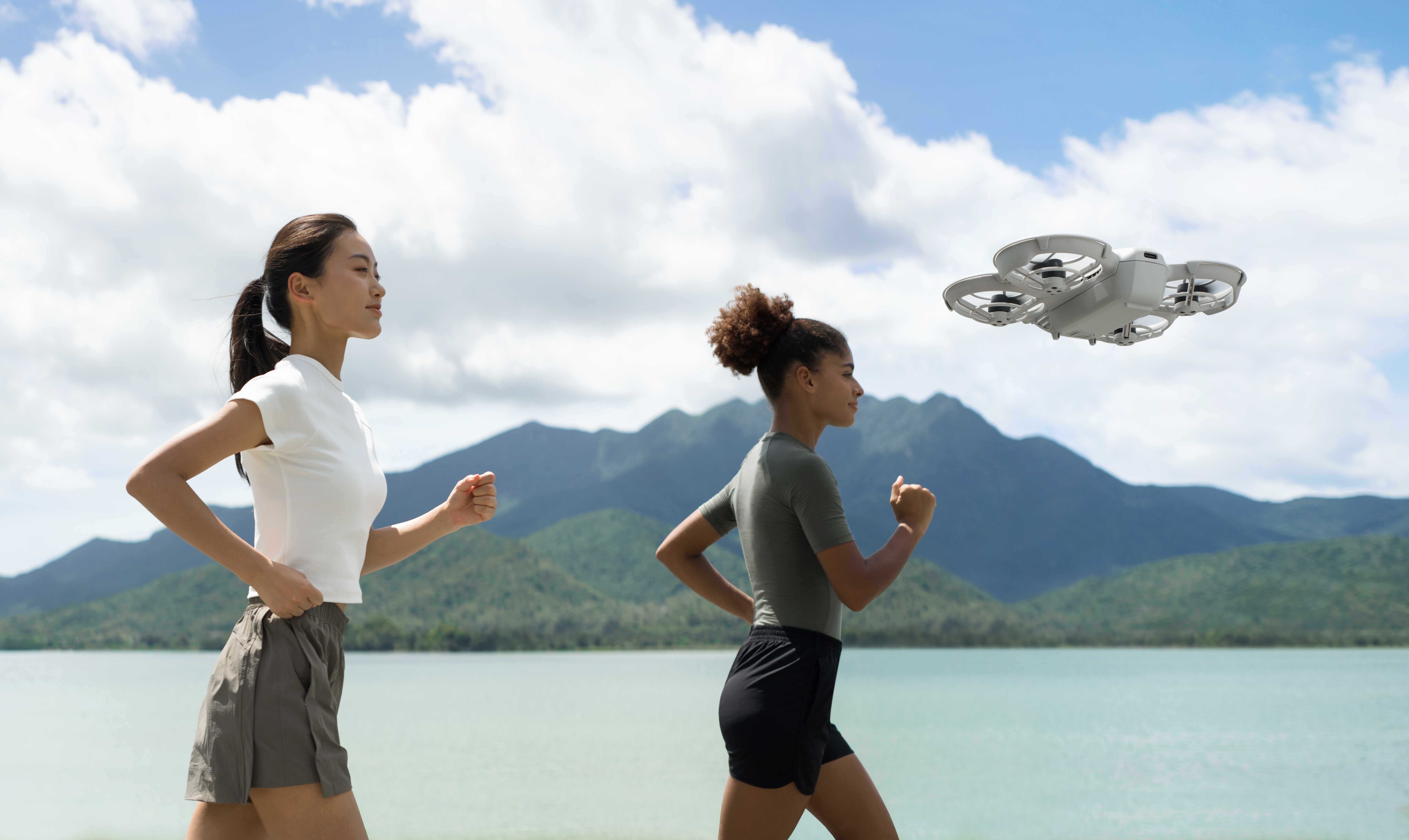 Zwei Frauen laufen am Wasser, Drohne fliegt über ihnen.