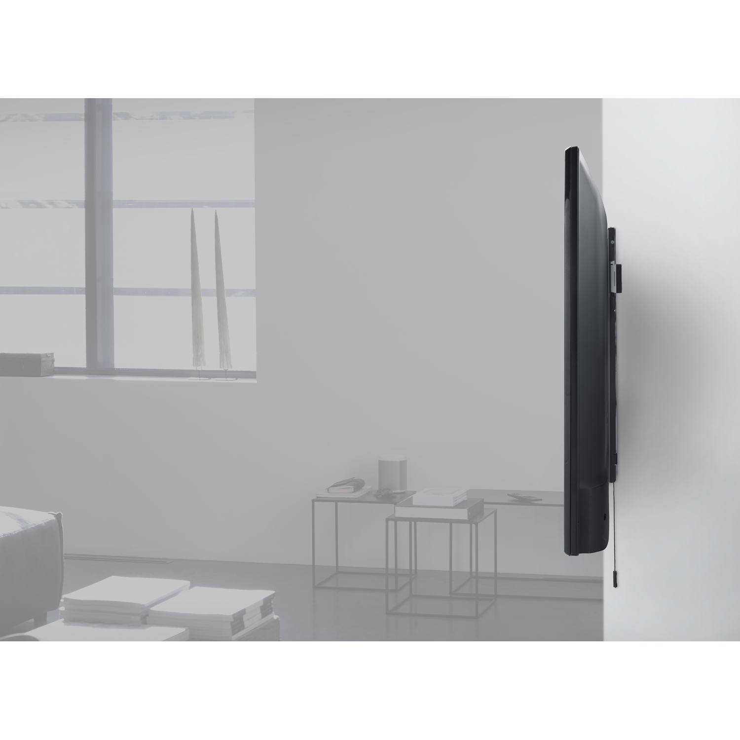 Een tv gemonteerd op een witte muur. De tv is zwart en de muur is effen. Twee verticale objecten aan de muur.