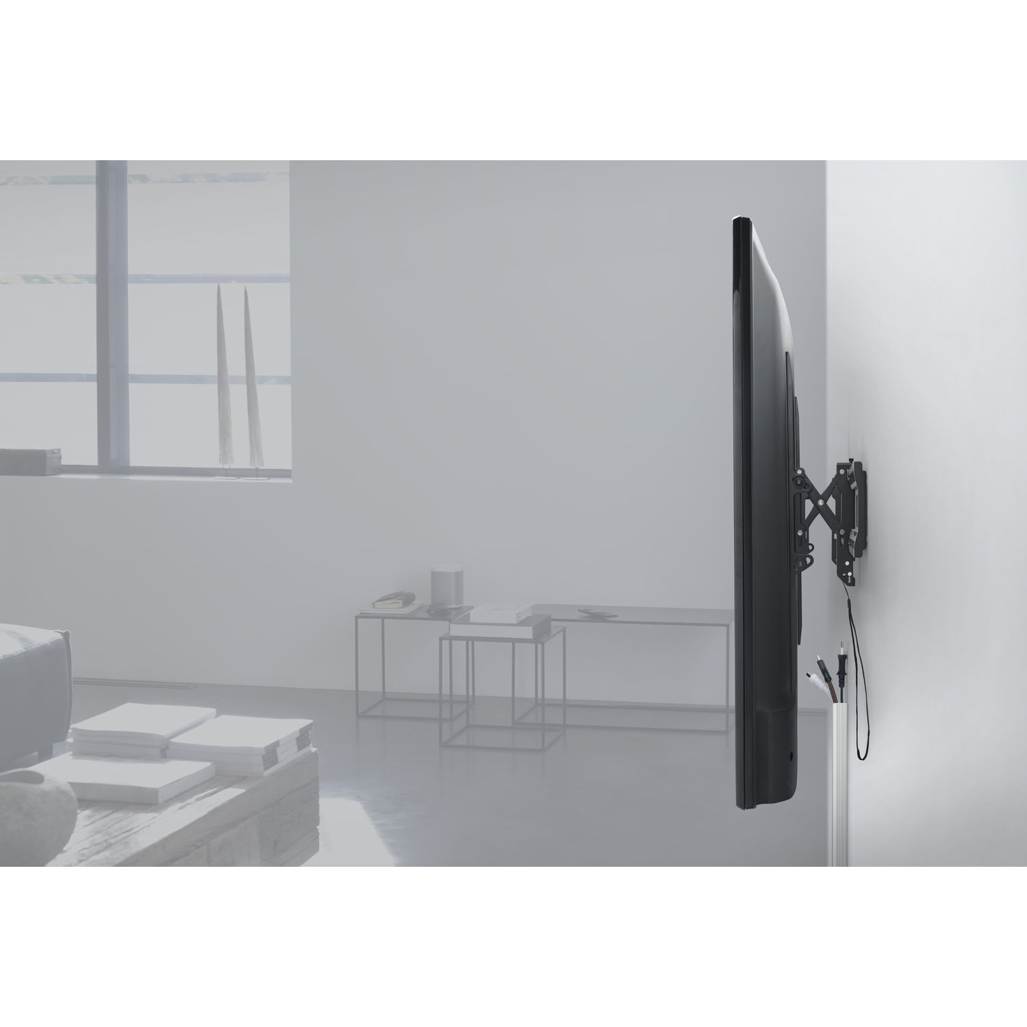Een grote tv aan de muur gemonteerd. De tv is zwart en de muur is wit. De achtergrond is wazig.